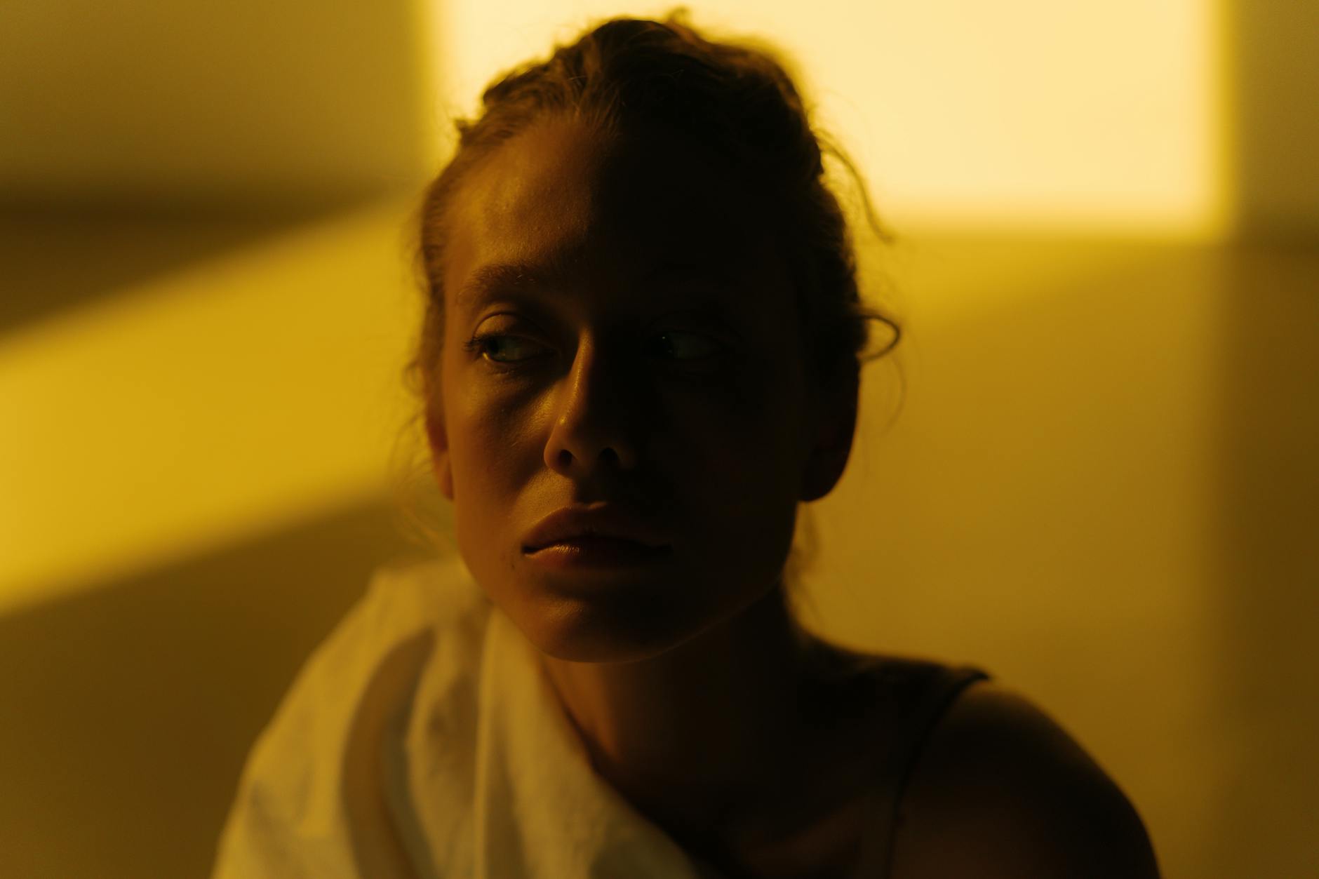 A contemplative woman in warm, dramatic lighting evokes a sense of introspection and emotion.