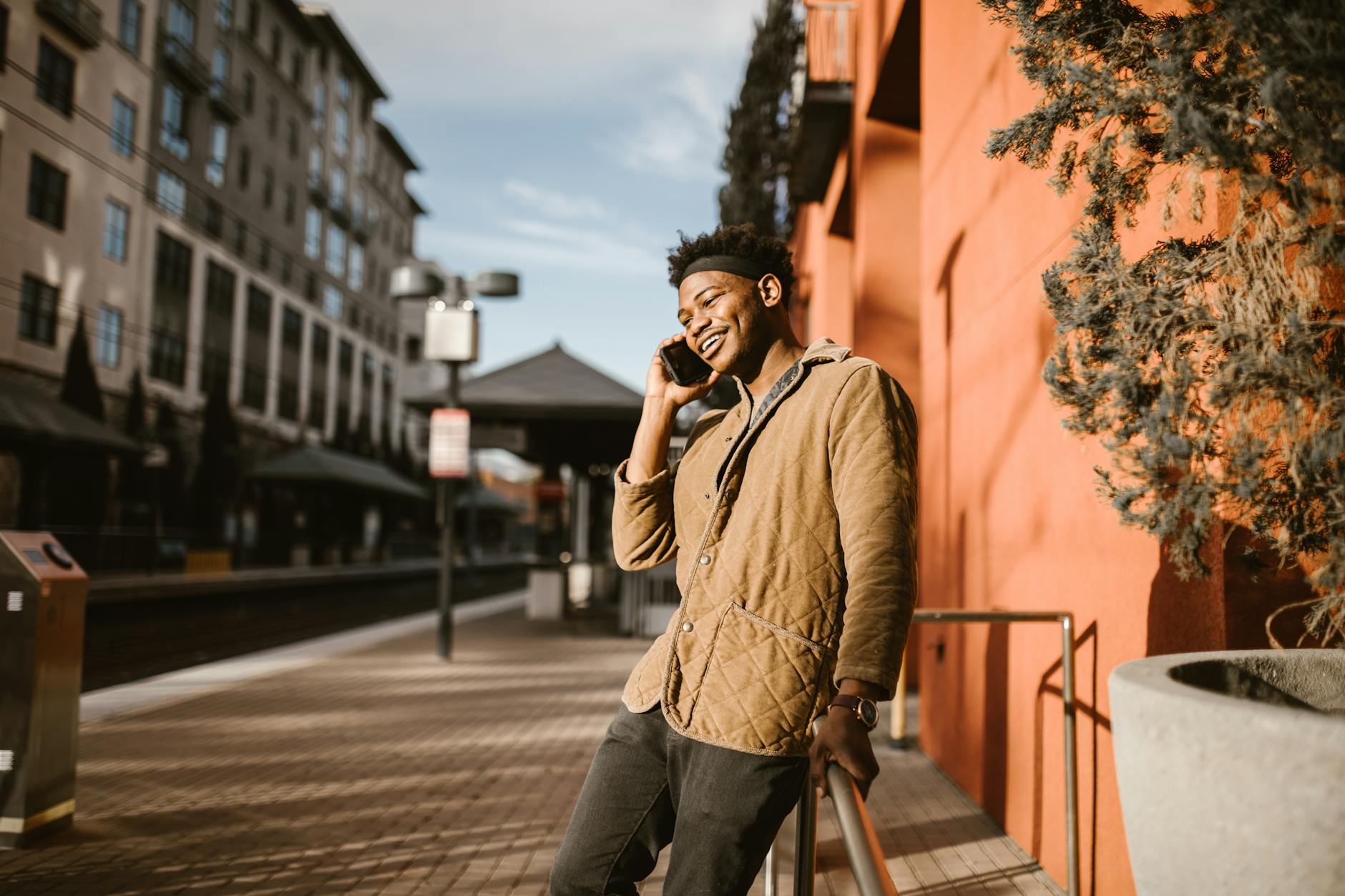Smiling young man in a city setting talking on his phone outdoors.