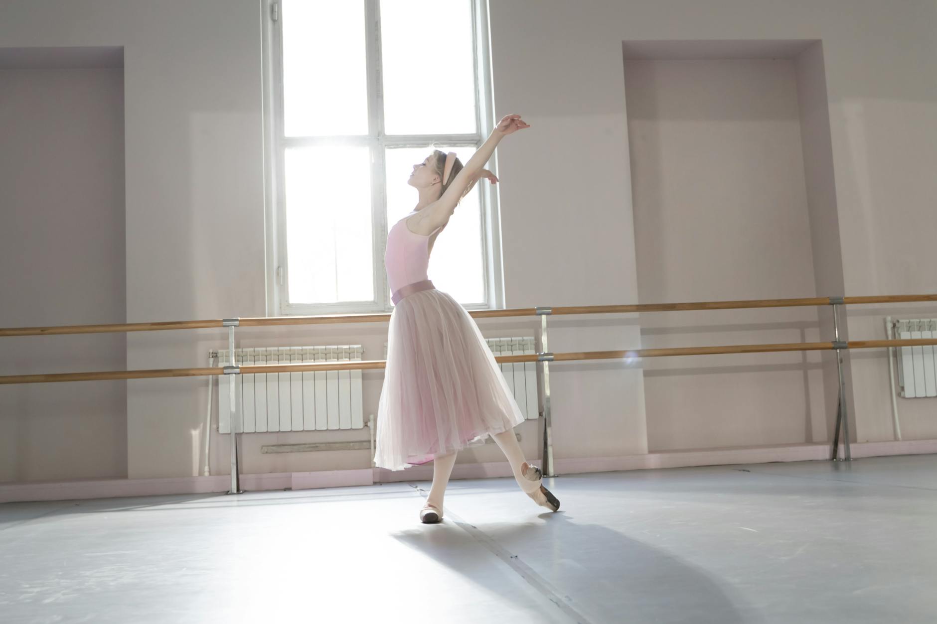Ballerina dancing elegantly in a sunlit dance studio showcasing grace and poise.