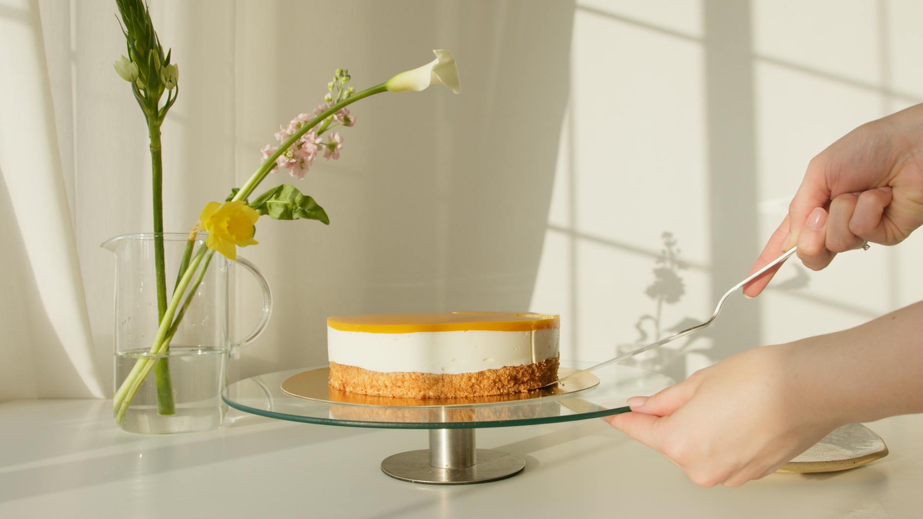 Elegant lemon cheesecake on a stand surrounded by natural flowers. Perfect for celebrations or culinary projects.