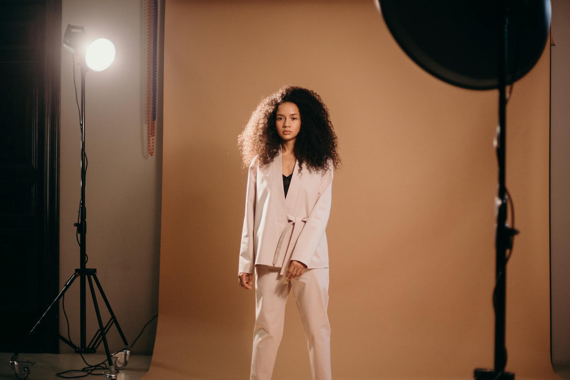 Elegant woman with afro hair posing in a professional studio setup.