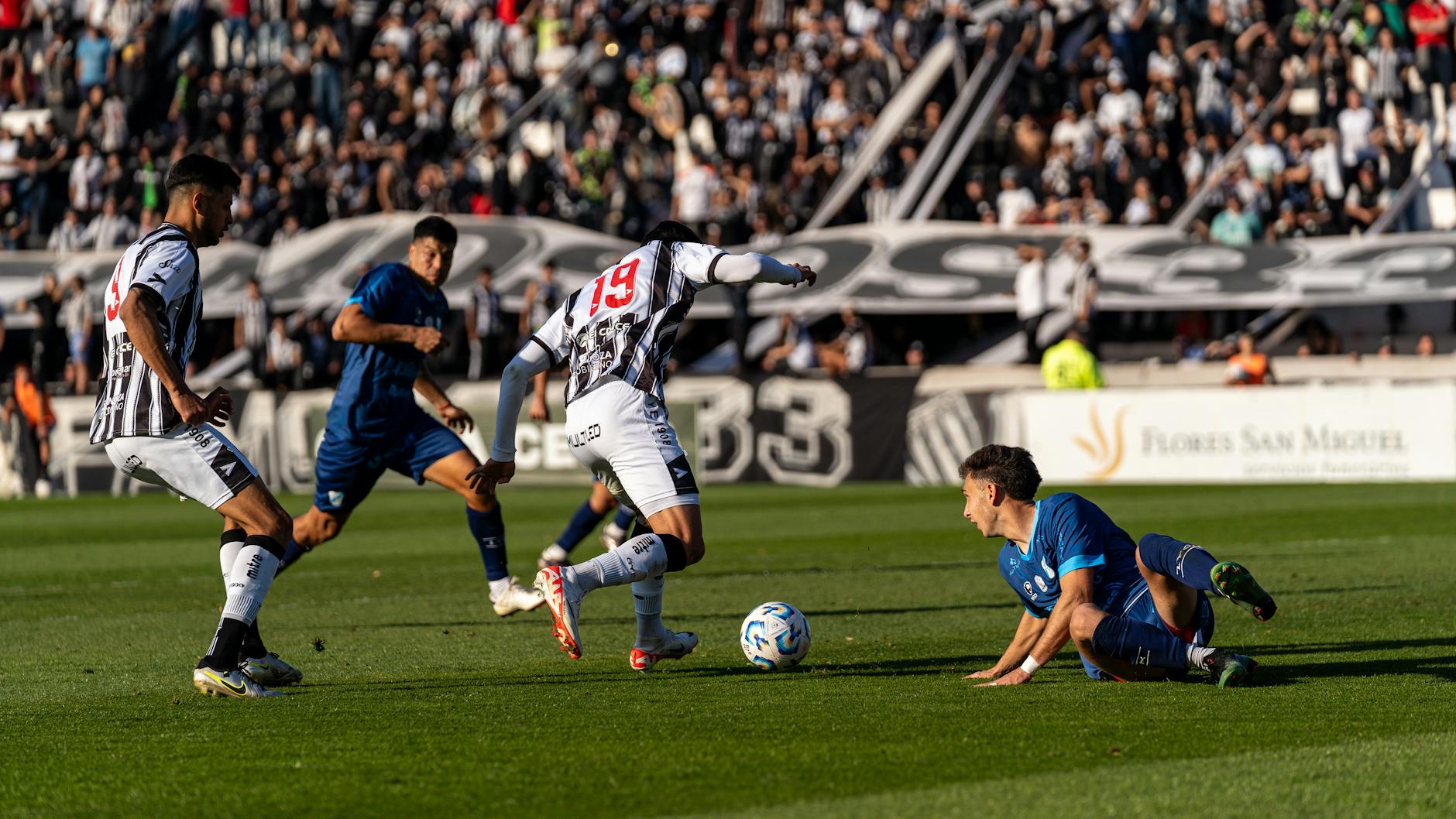 Intense football match with players in action during a sunny day.