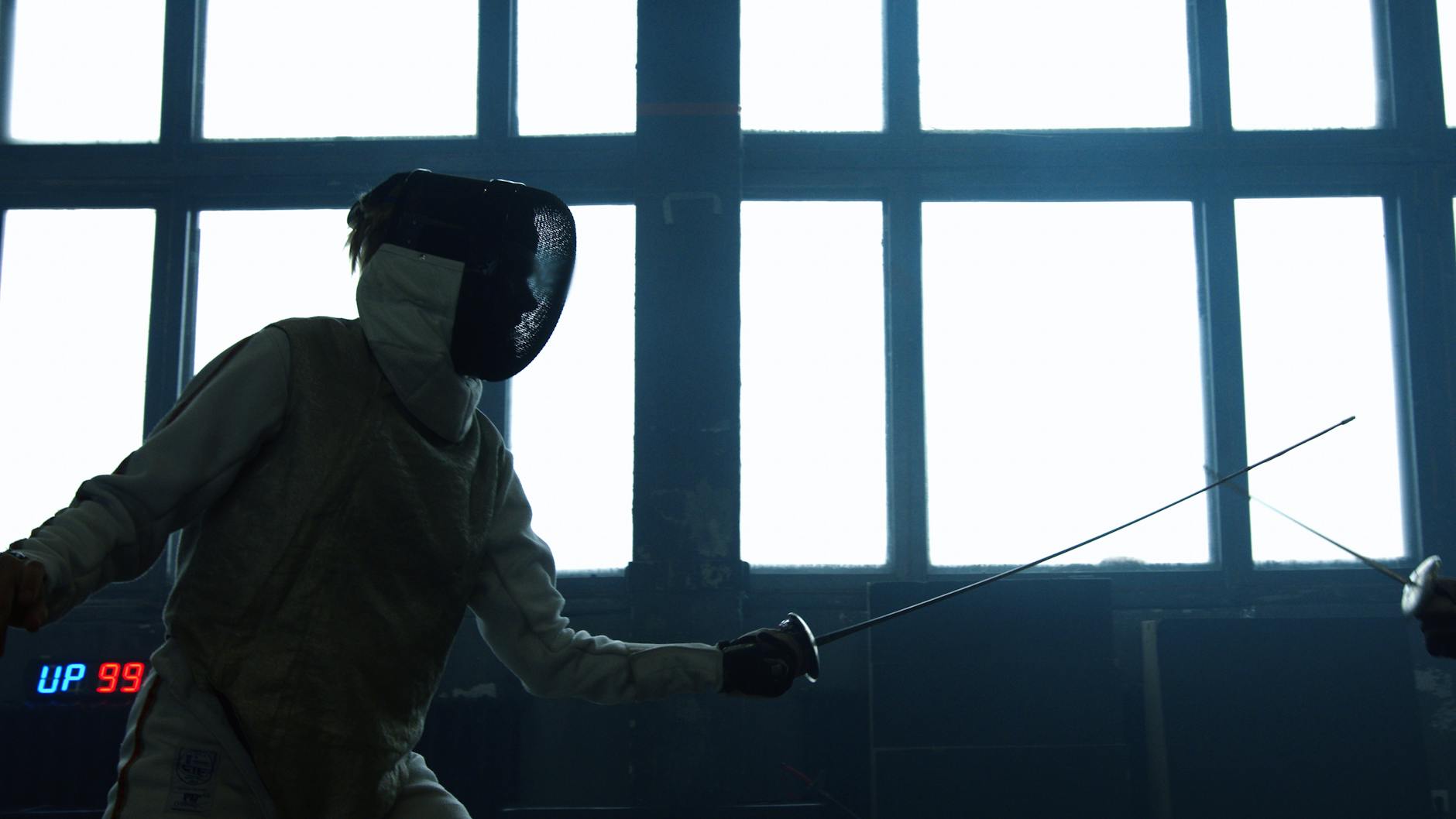 Fencers duel in a dramatic indoor setting, highlighting expertise and focus.