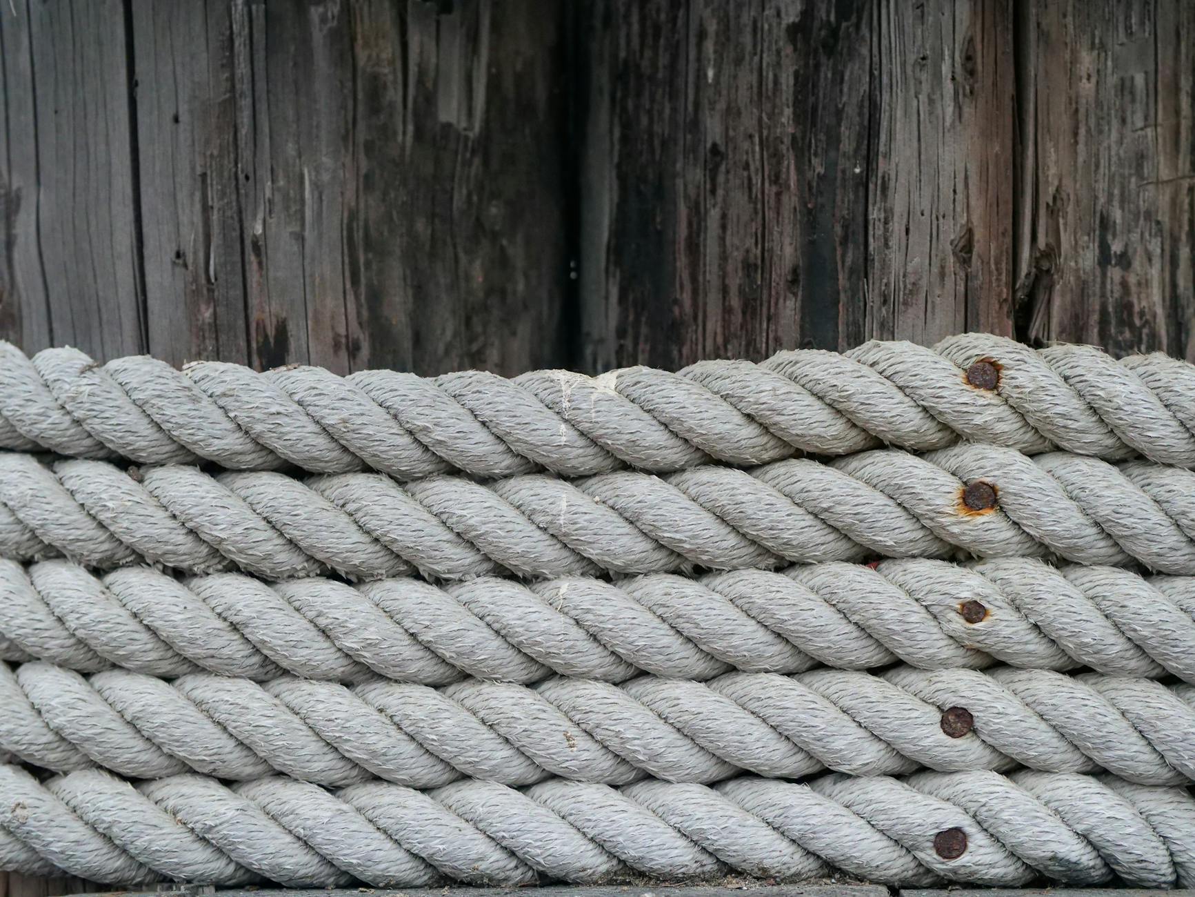 Detailed view of coiled nautical ropes against a rustic wooden background, emphasizing texture.
