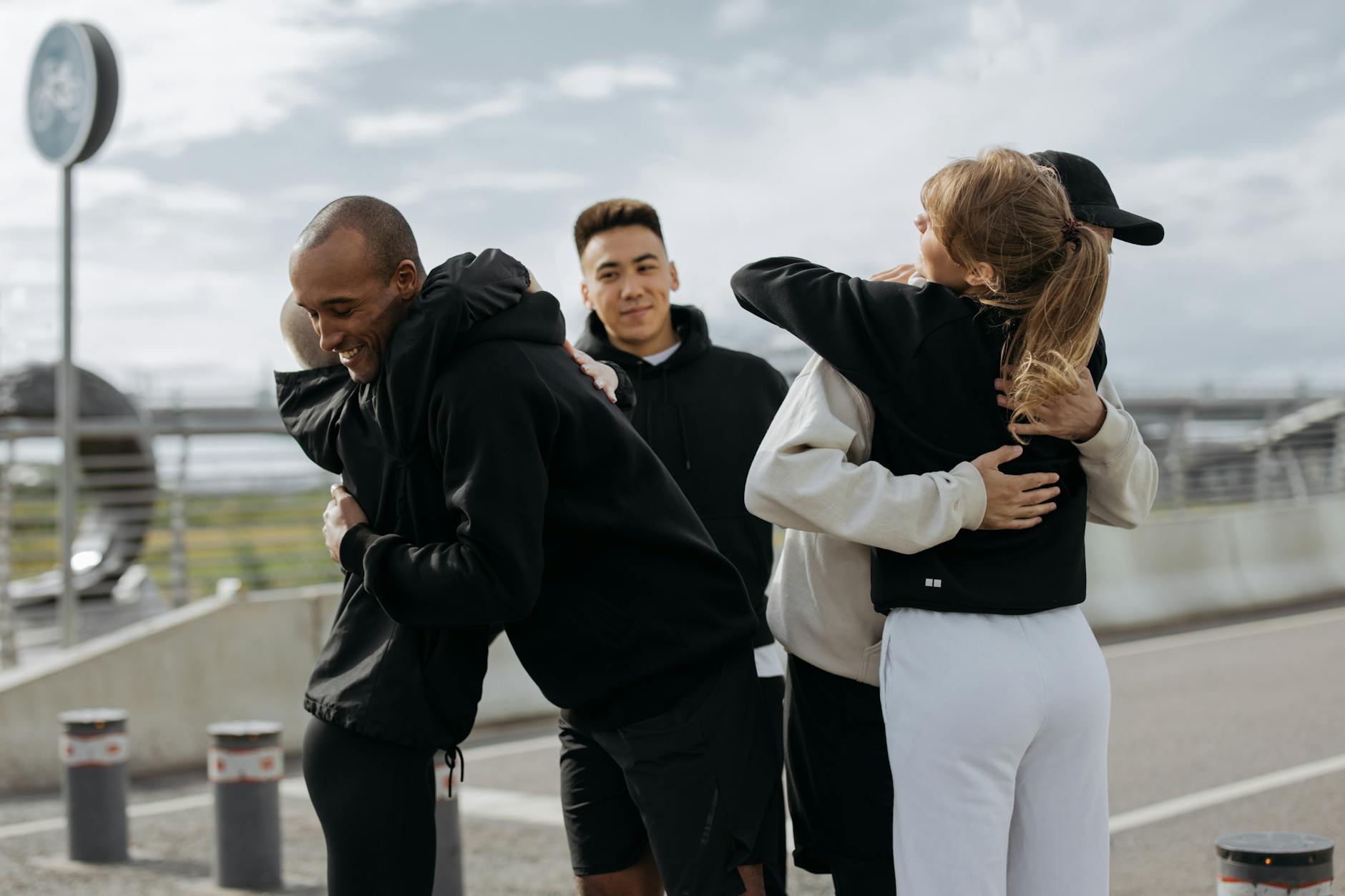 Four friends hugging and smiling on a city street, showing friendship and joy.