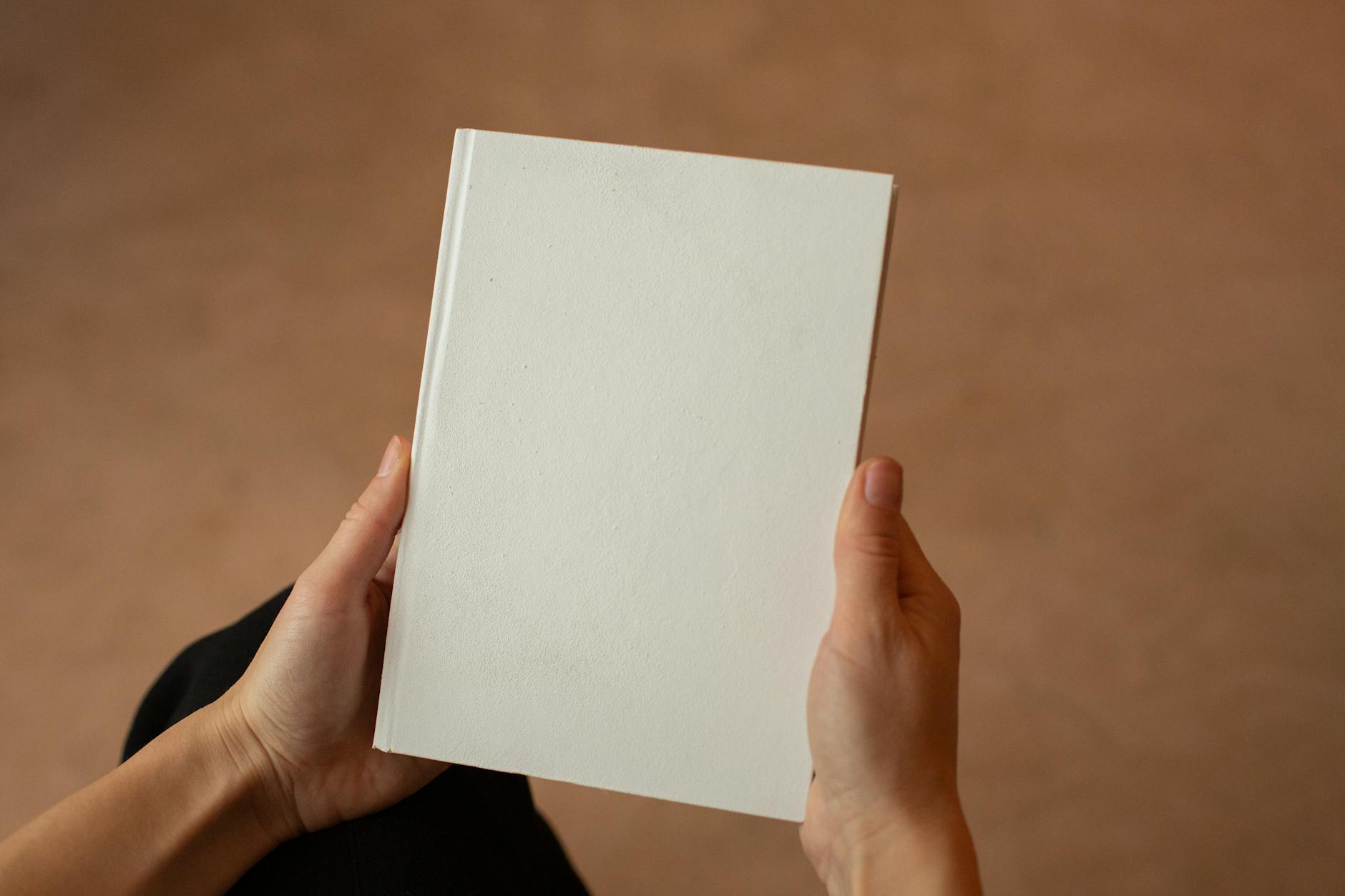A person holding a blank hardcover book. Perfect for mockup and design templates.
