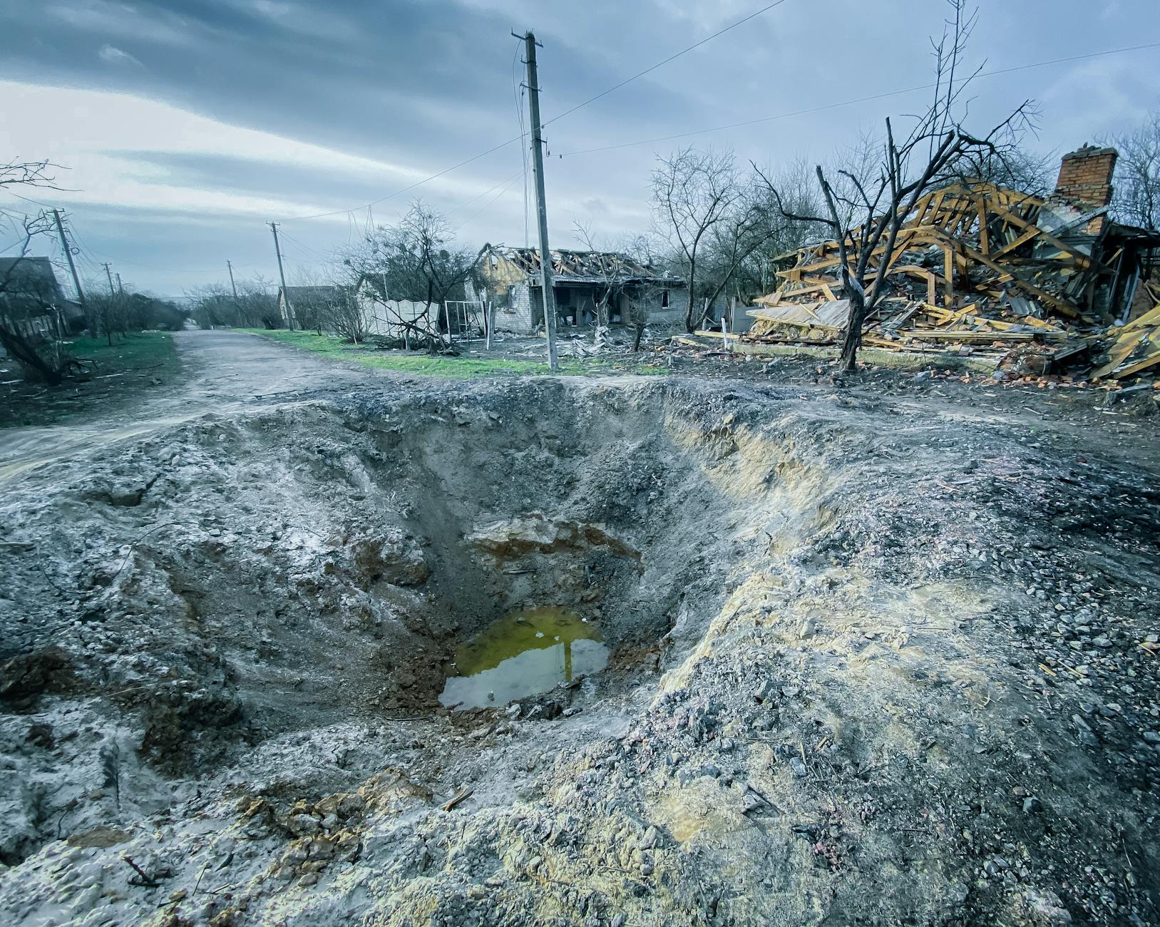 A large crater and destroyed homes mark the aftermath of conflict in Makariv, Kyiv Oblast, Ukraine.