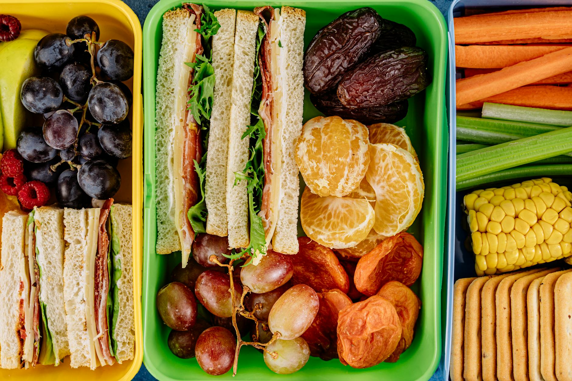 Colorful lunchbox filled with sandwiches, fresh fruits, and vegetables, perfect for a healthy meal.