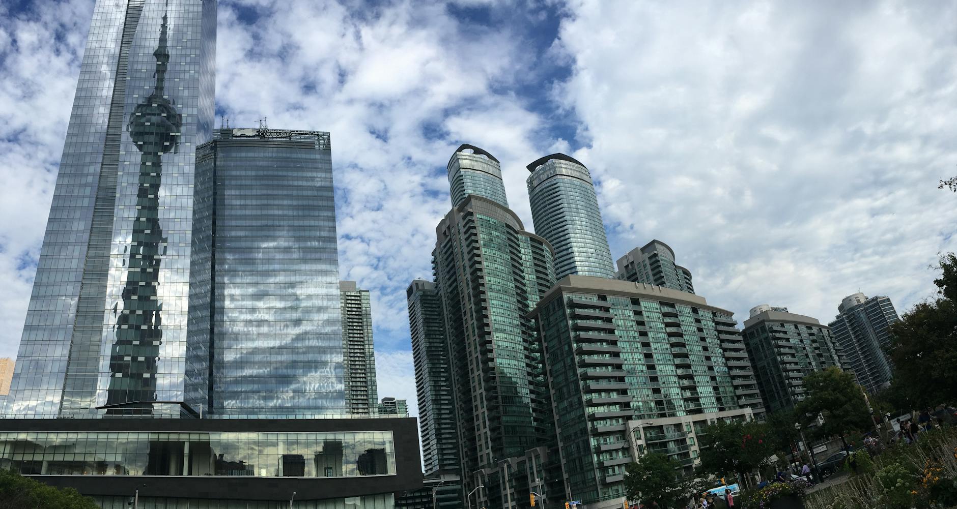 A stunning view of Toronto's modern skyline reflecting the iconic CN Tower on a bright day.