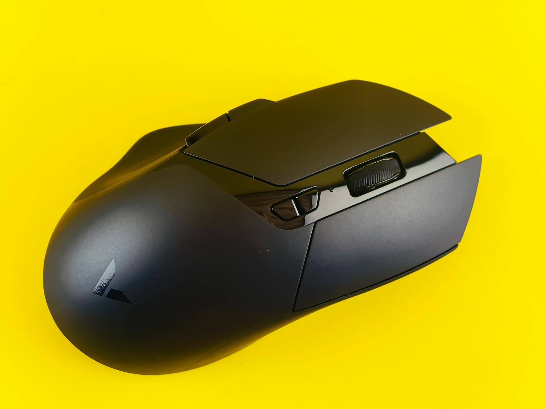 Modern black gaming mouse against vibrant yellow backdrop, showcasing innovative design.