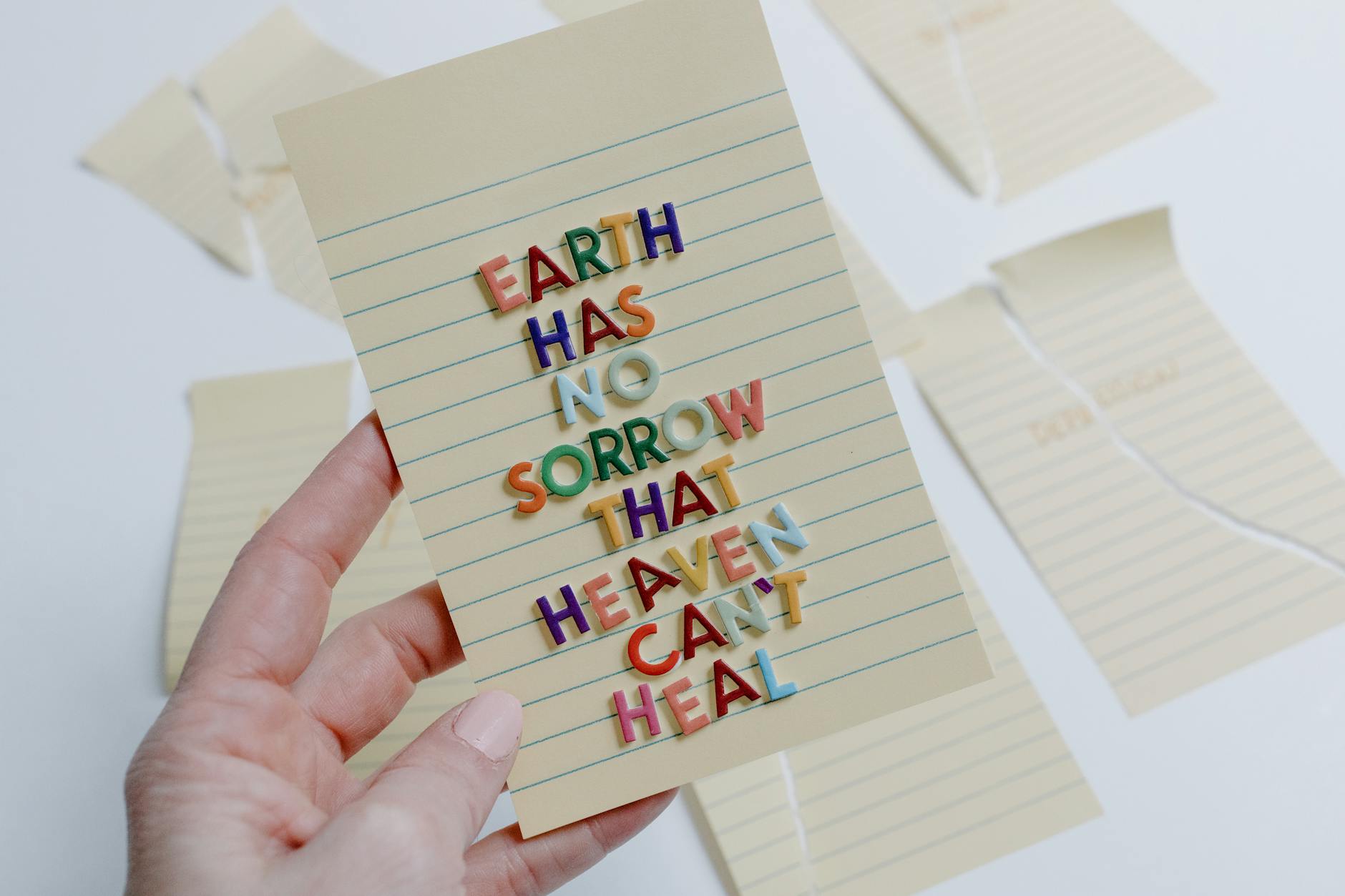 A hand holding a card with an inspirational quote using colorful letters.