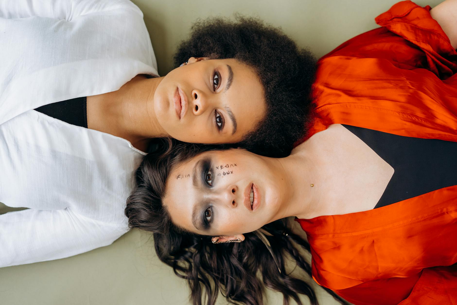 Two women in white and red outfits lying down, highlighting diversity and togetherness.