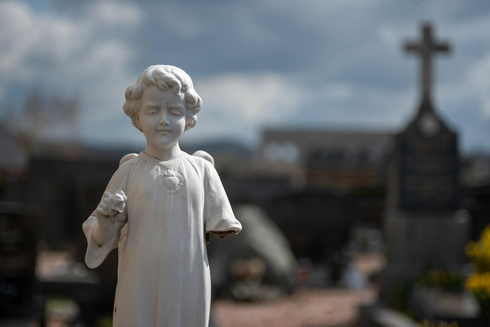 Serene marble angel statue in Holset cemetery under a moody sky.