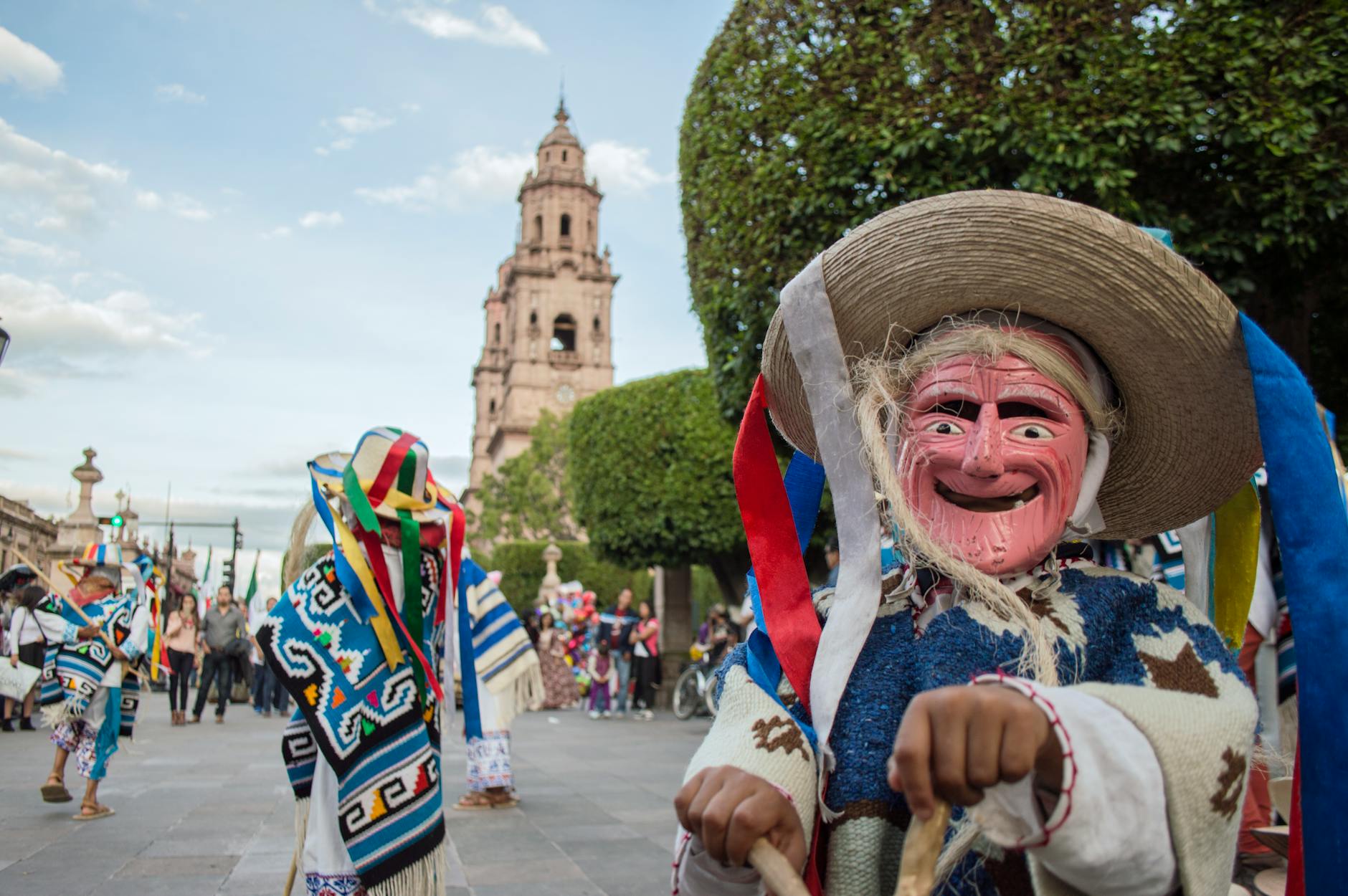 A lively street festival with participants in traditional masks and costumes celebrating a cultural parade.