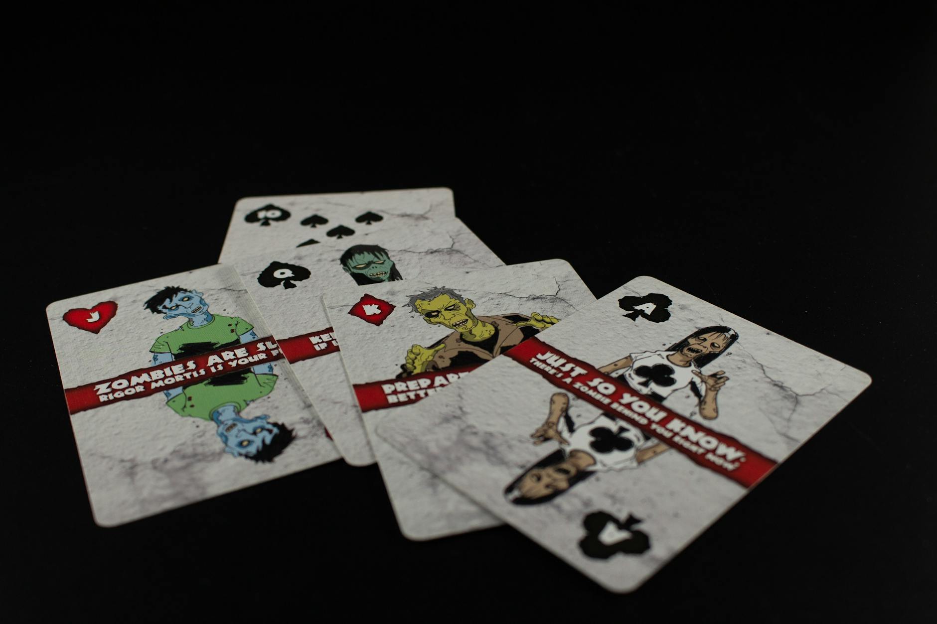 A dramatic still life of zombie-themed playing cards on a black background creates a spooky ambiance.
