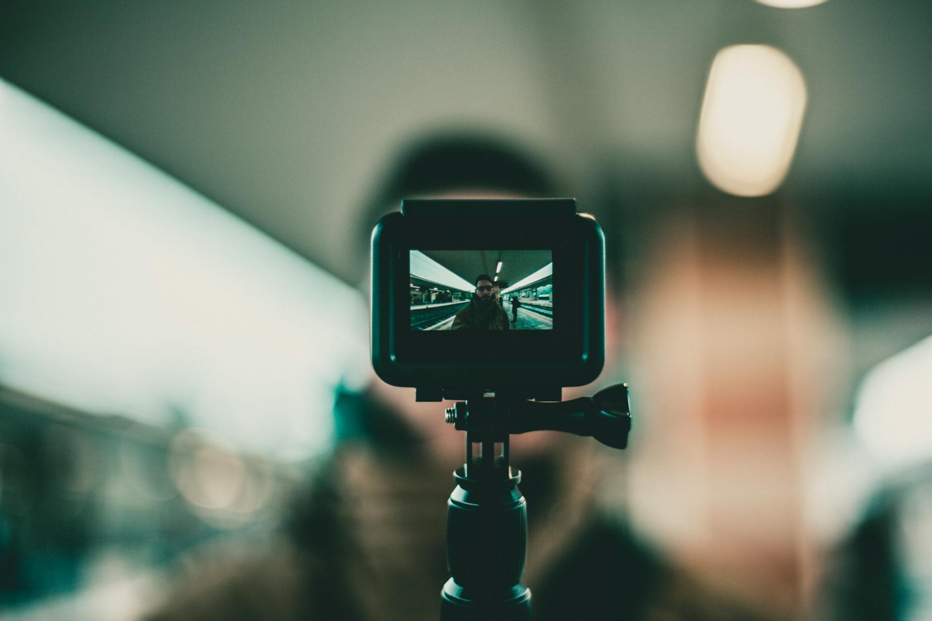 A focused action camera recording a vlogger at a train station with blurred background.