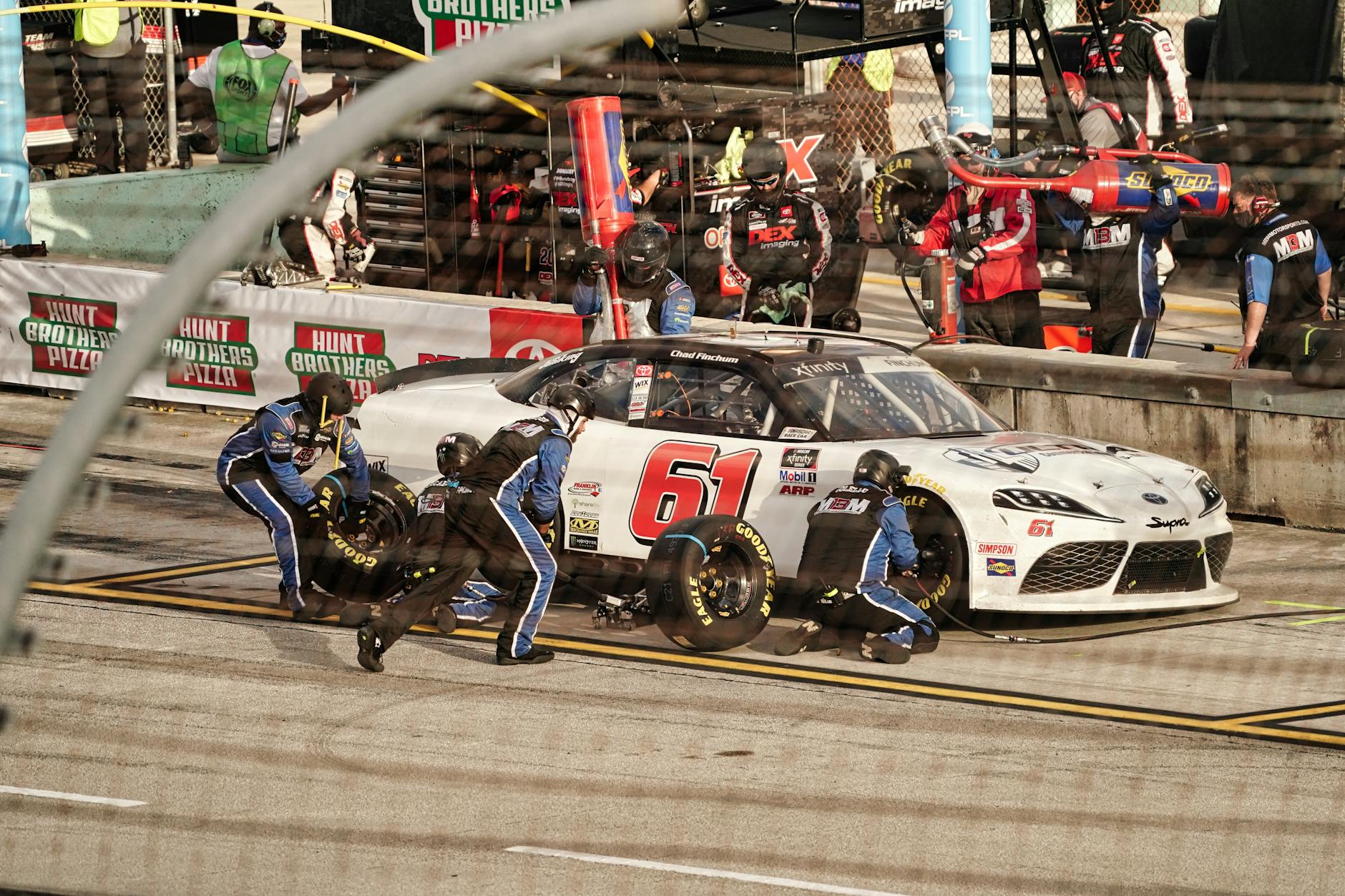 High-energy pit stop with a race car at a Miami NASCAR event.