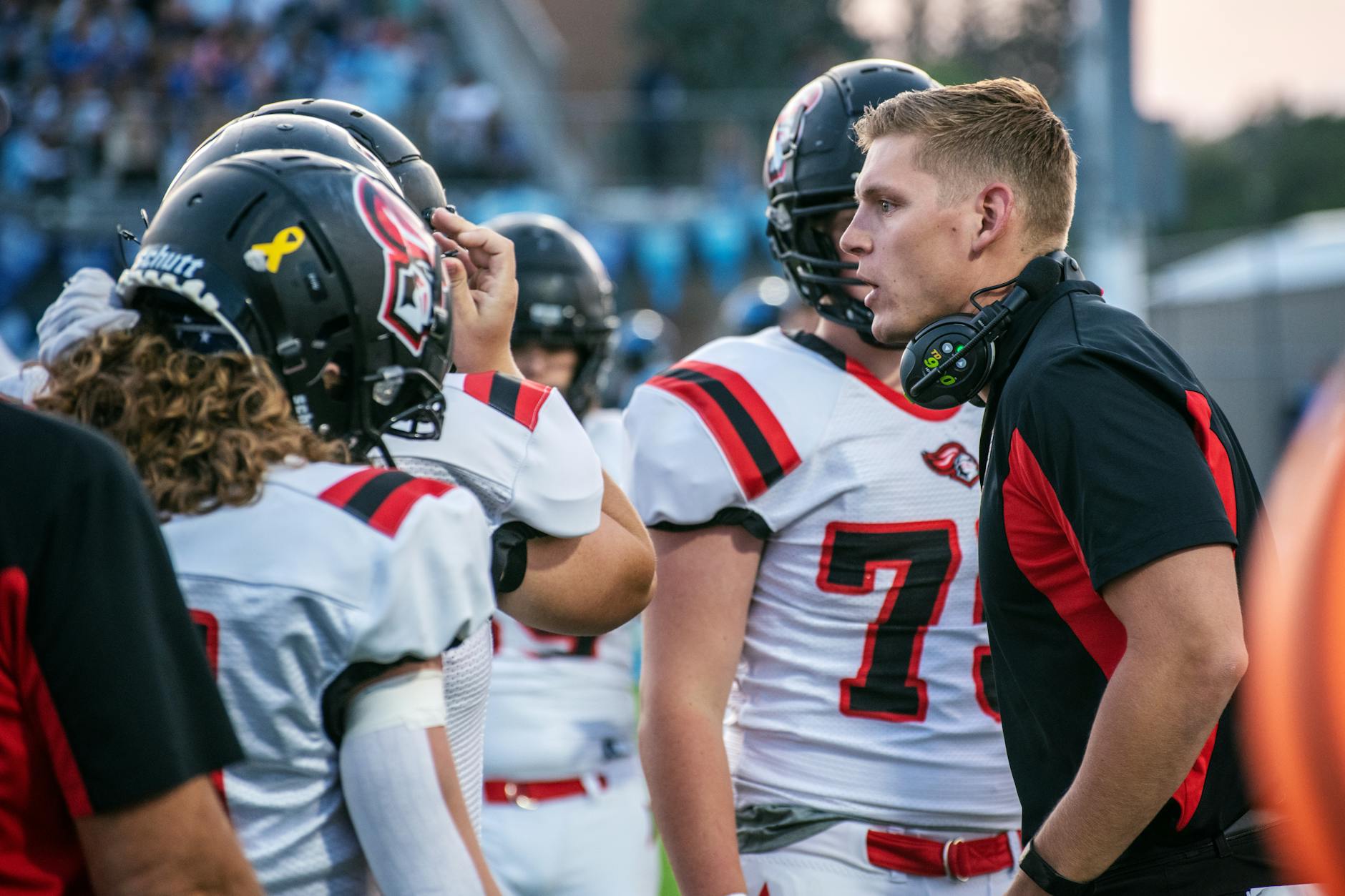 Football coach motivating players on field during a game in Idaho Falls.