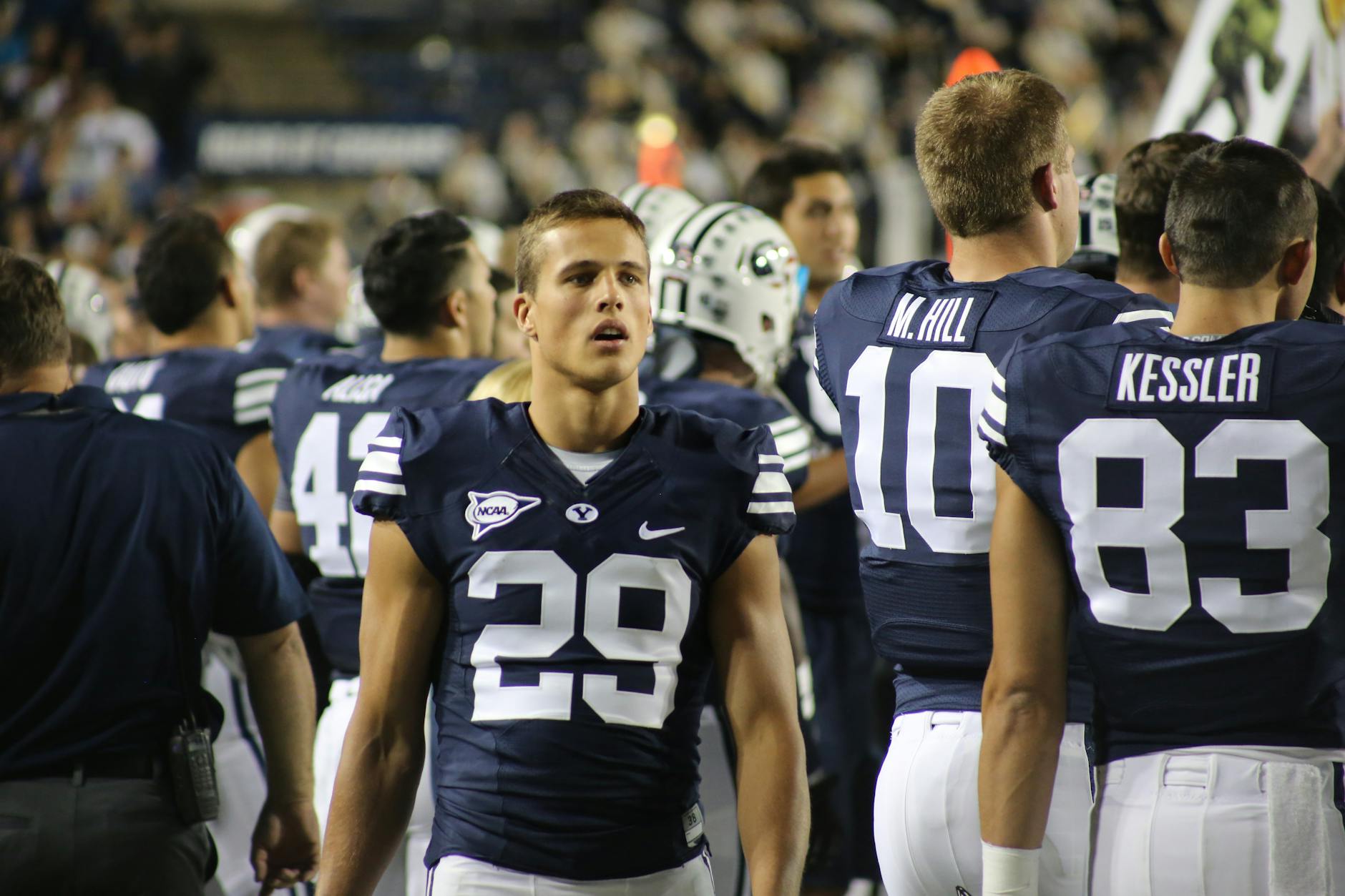 A team of American football players standing on the sidelines during a game.