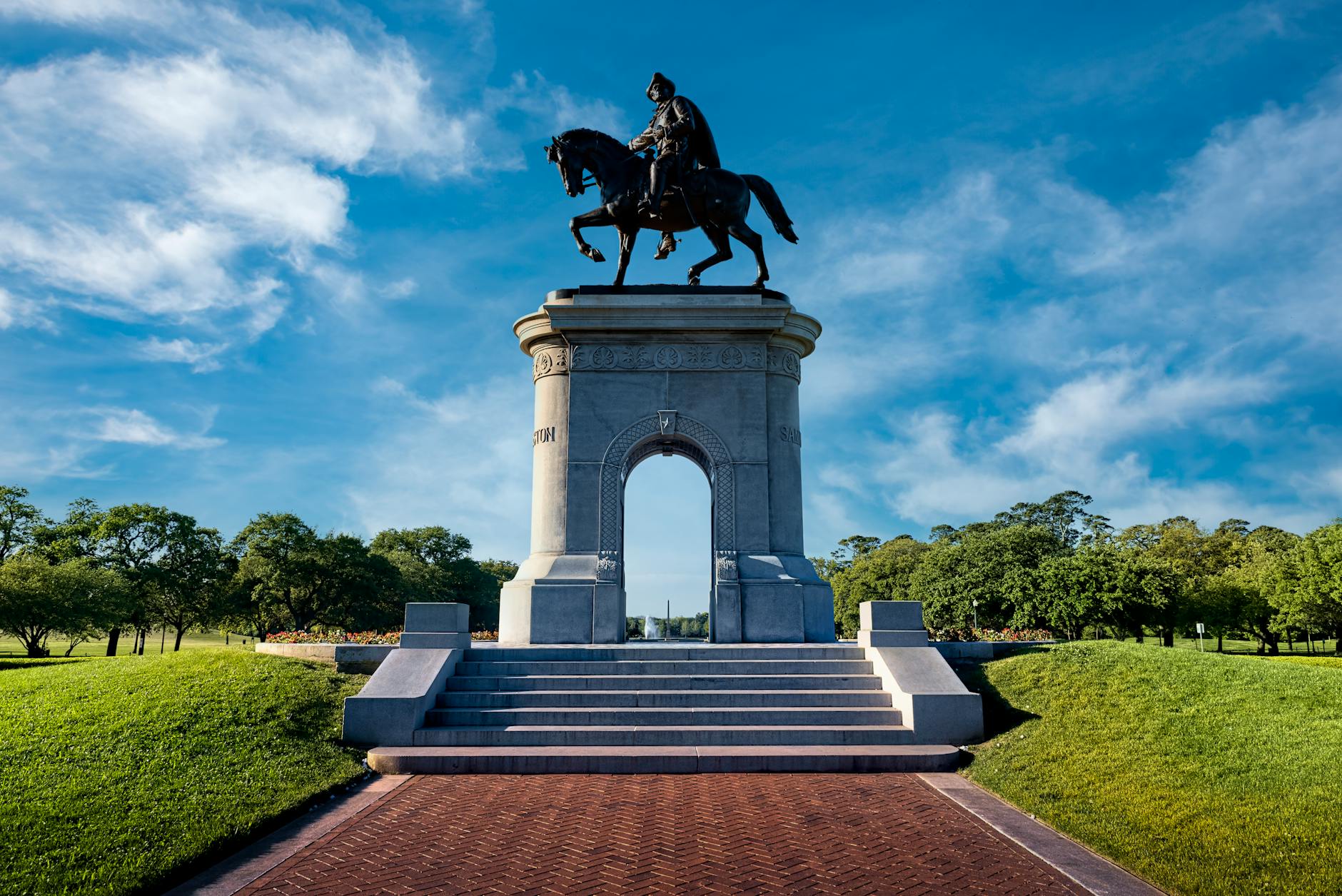 The iconic Sam Houston monument in the scenic Hermann Park, Houston, with a clear blue sky backdrop.
