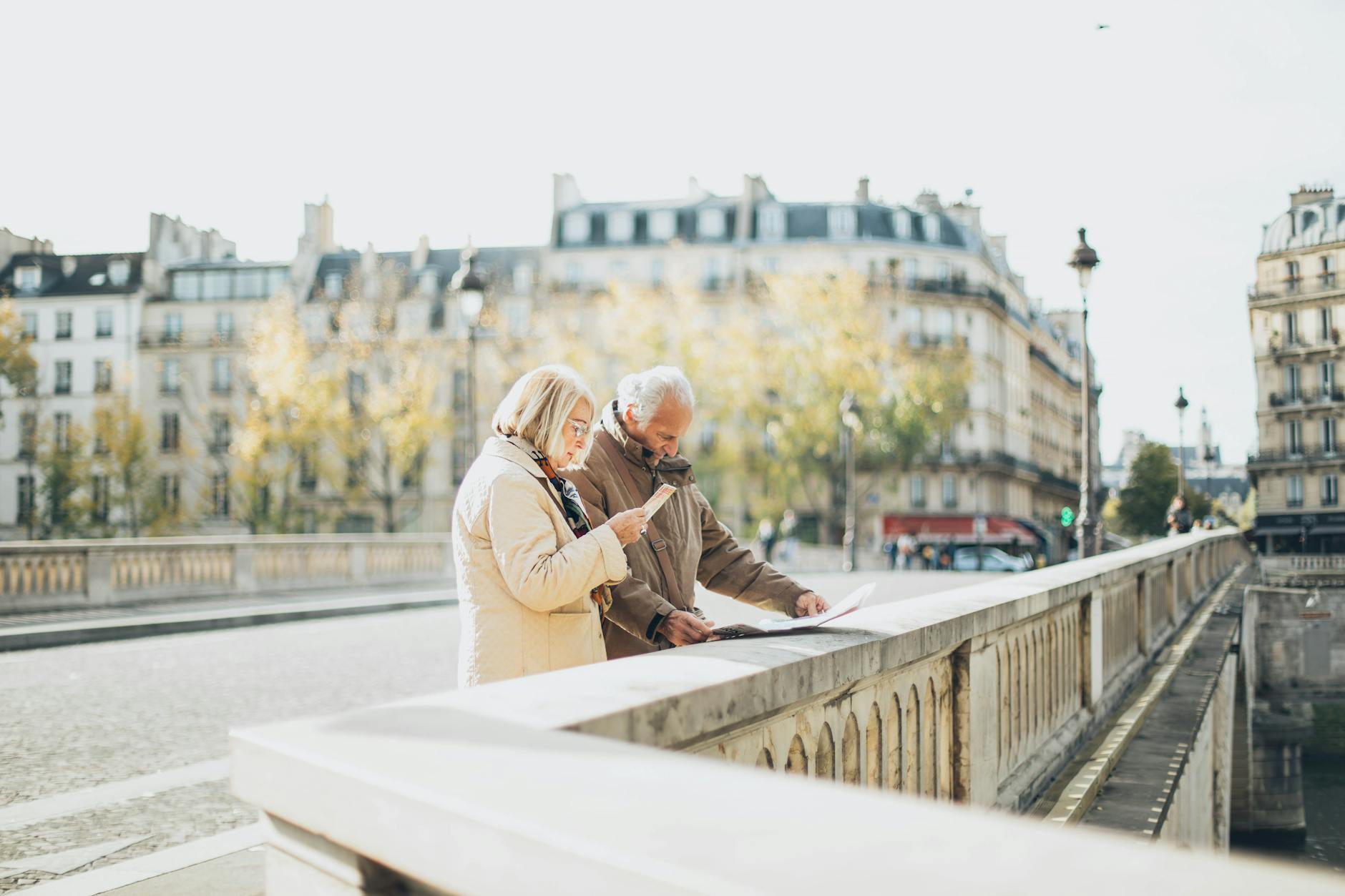 An elderly couple using a map in a scenic European city with historical architecture.