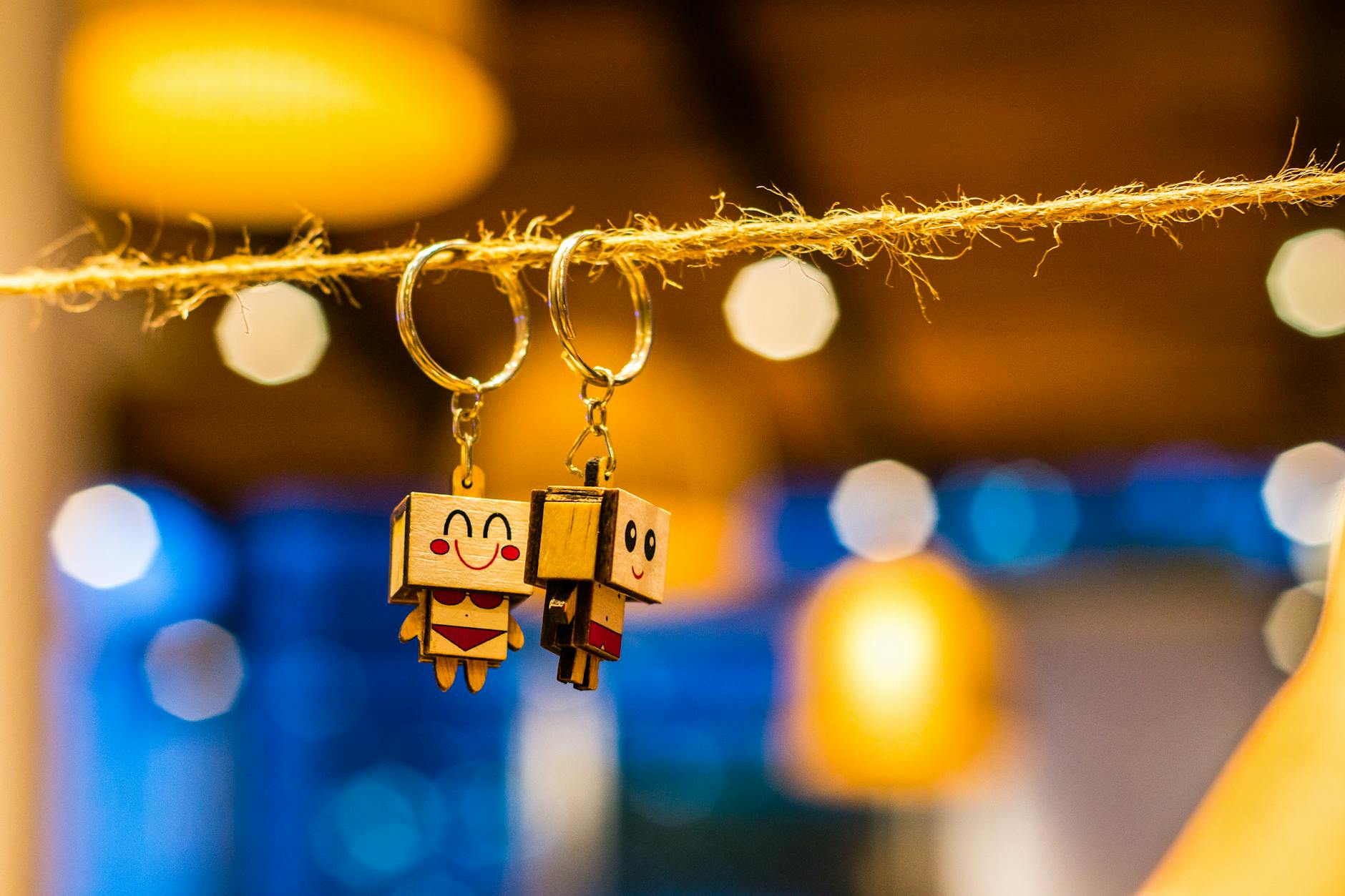 Close-up of cute toy keychains hanging on a string with bright bokeh lights in the background.