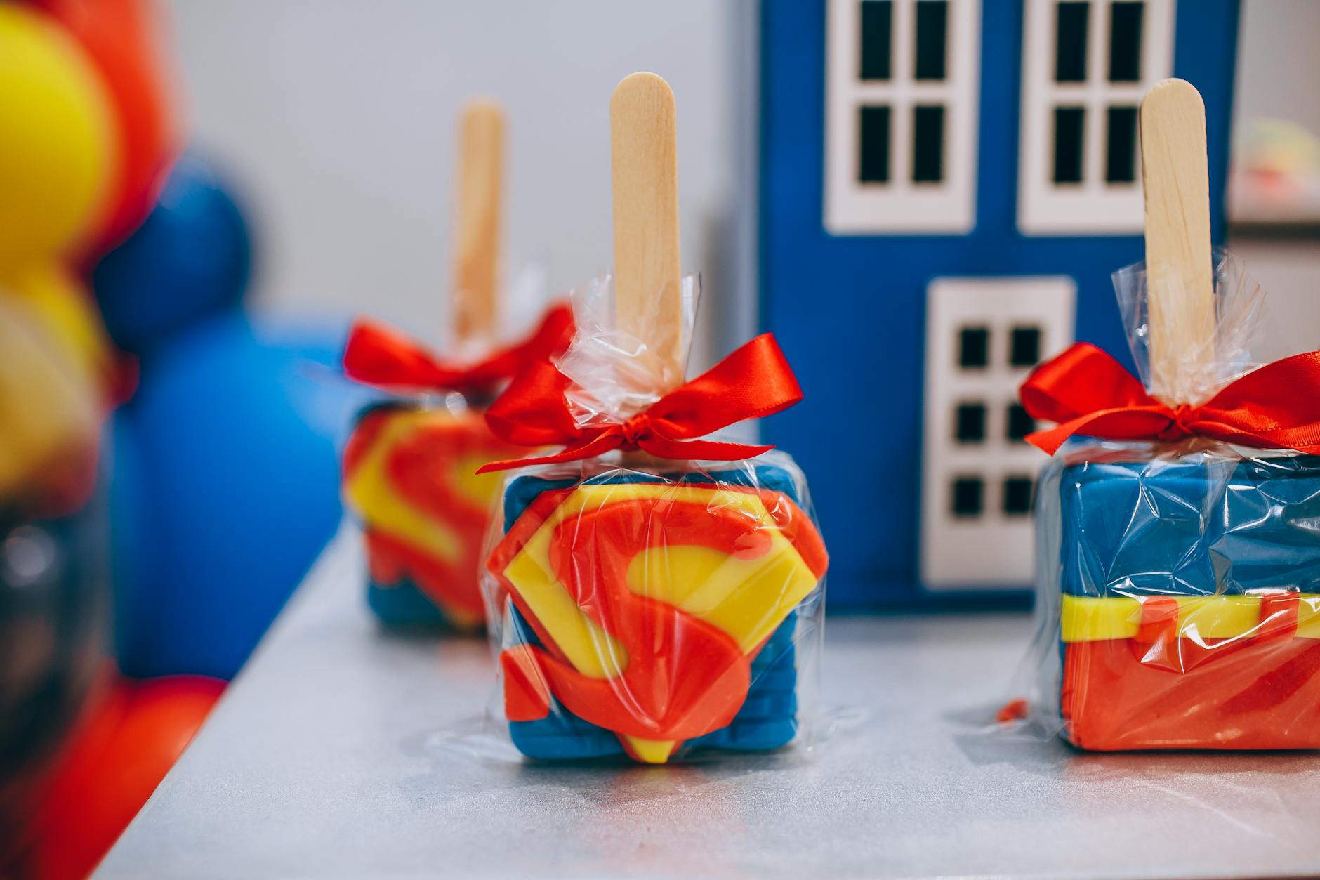 Superman-themed square lollipops with red bow, perfect for birthday celebrations.