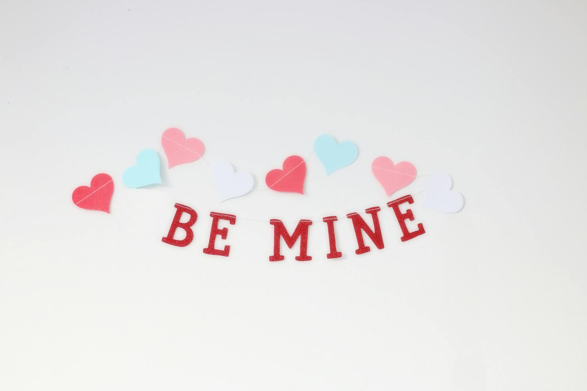 Charming arrangement of colorful hearts and 'Be Mine' text, perfect for Valentine's Day.
