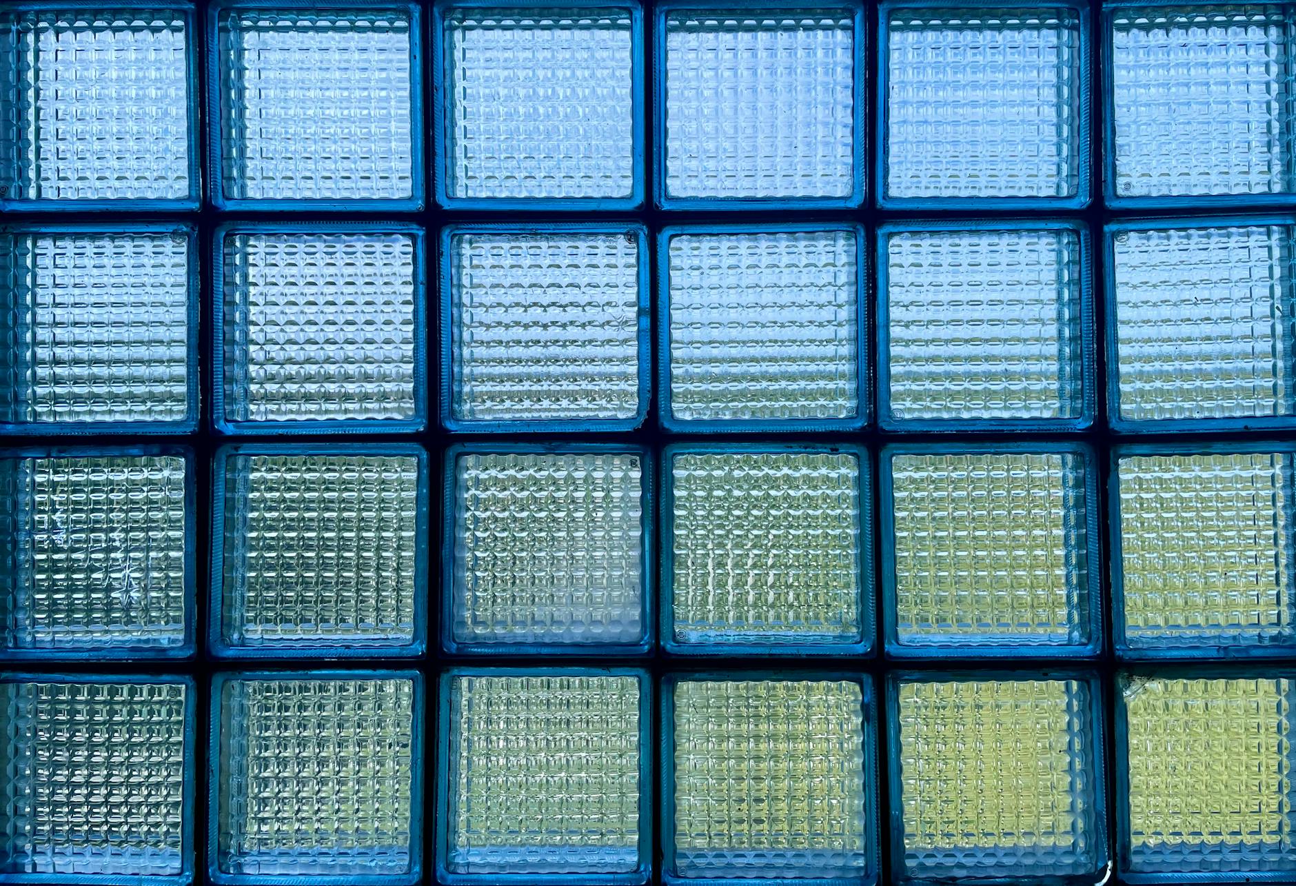 Abstract view of a glass block window with a blue tint, showcasing light and pattern.