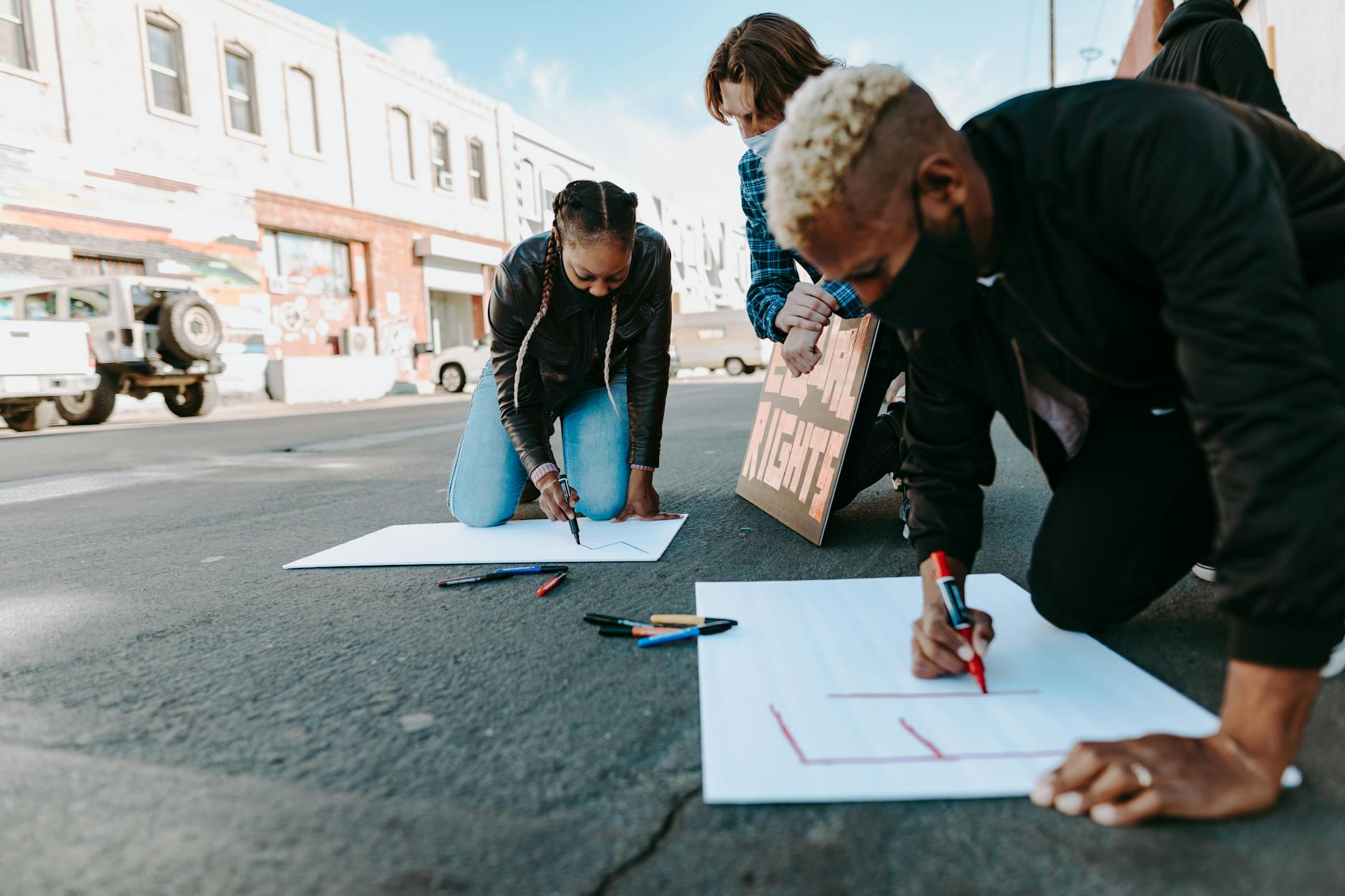 Protesters creating signs for a street demonstration in an urban area.