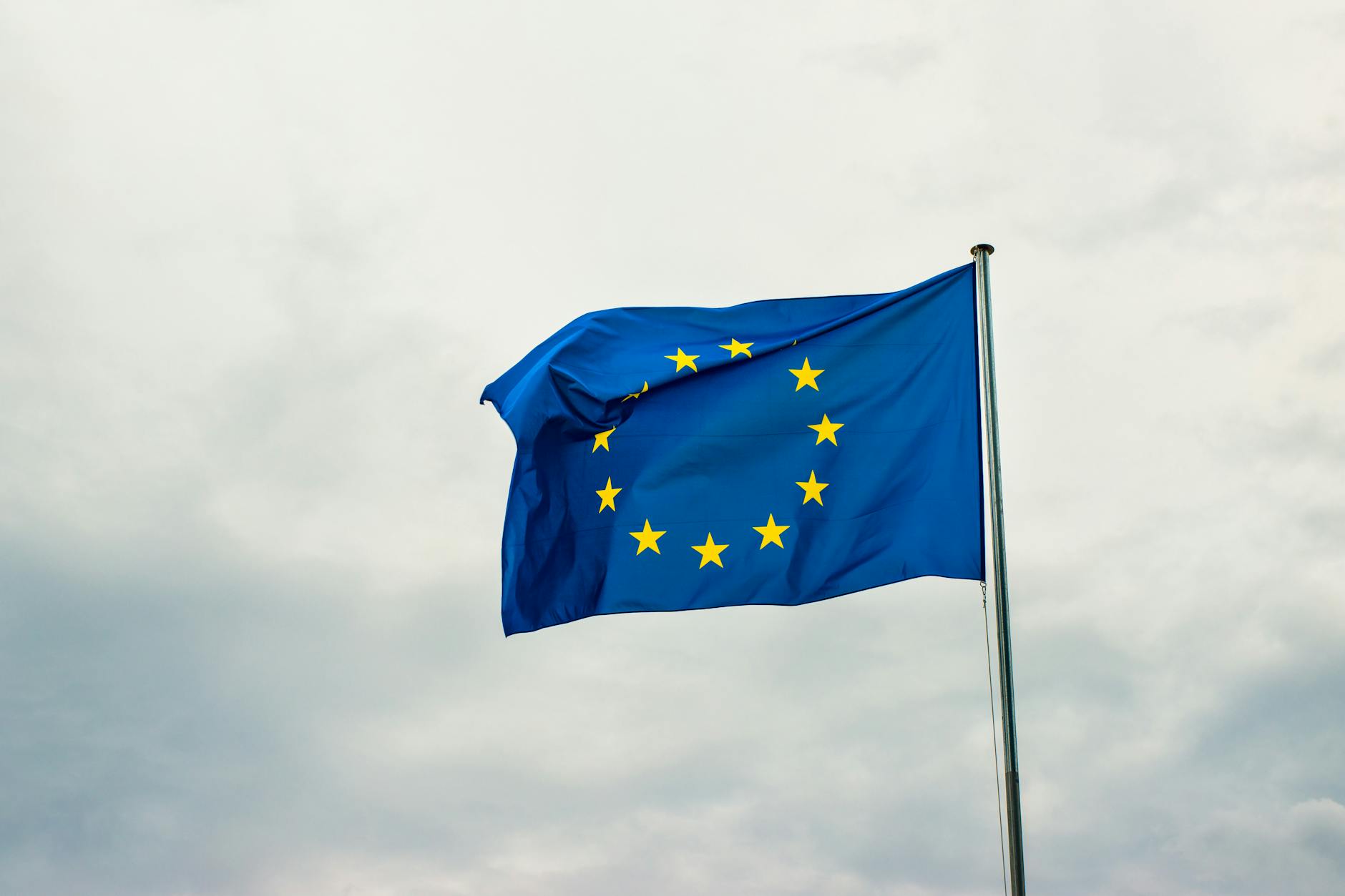 European Union flag waving vividly against a cloudy sky in Strasbourg, France.