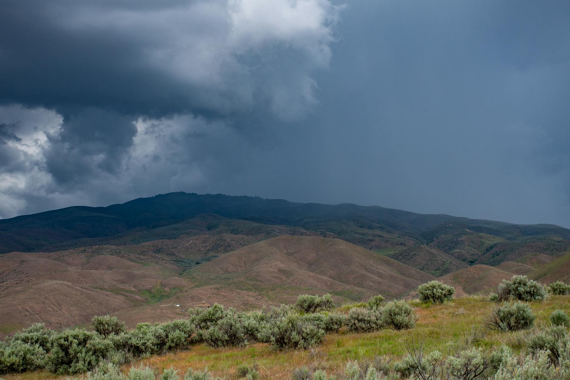 A picturesque view of storm clouds looming over a peaceful mountain landscape, capturing nature's raw beauty.