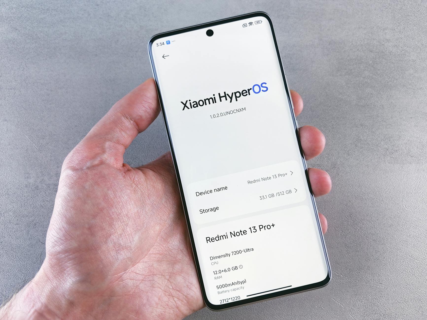 Close-up of a hand holding a smartphone displaying Xiaomi HyperOS on the screen.
