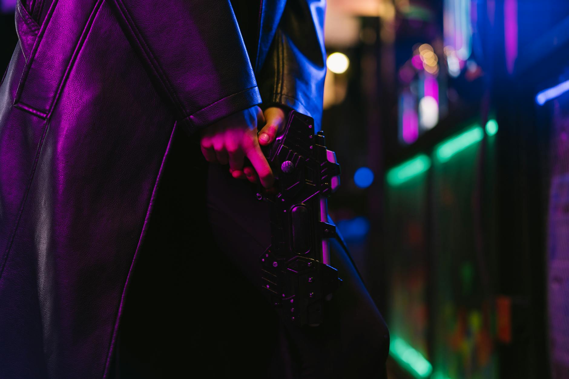 Dark, cyberpunk image of a futuristic style person holding a gun in neon light.