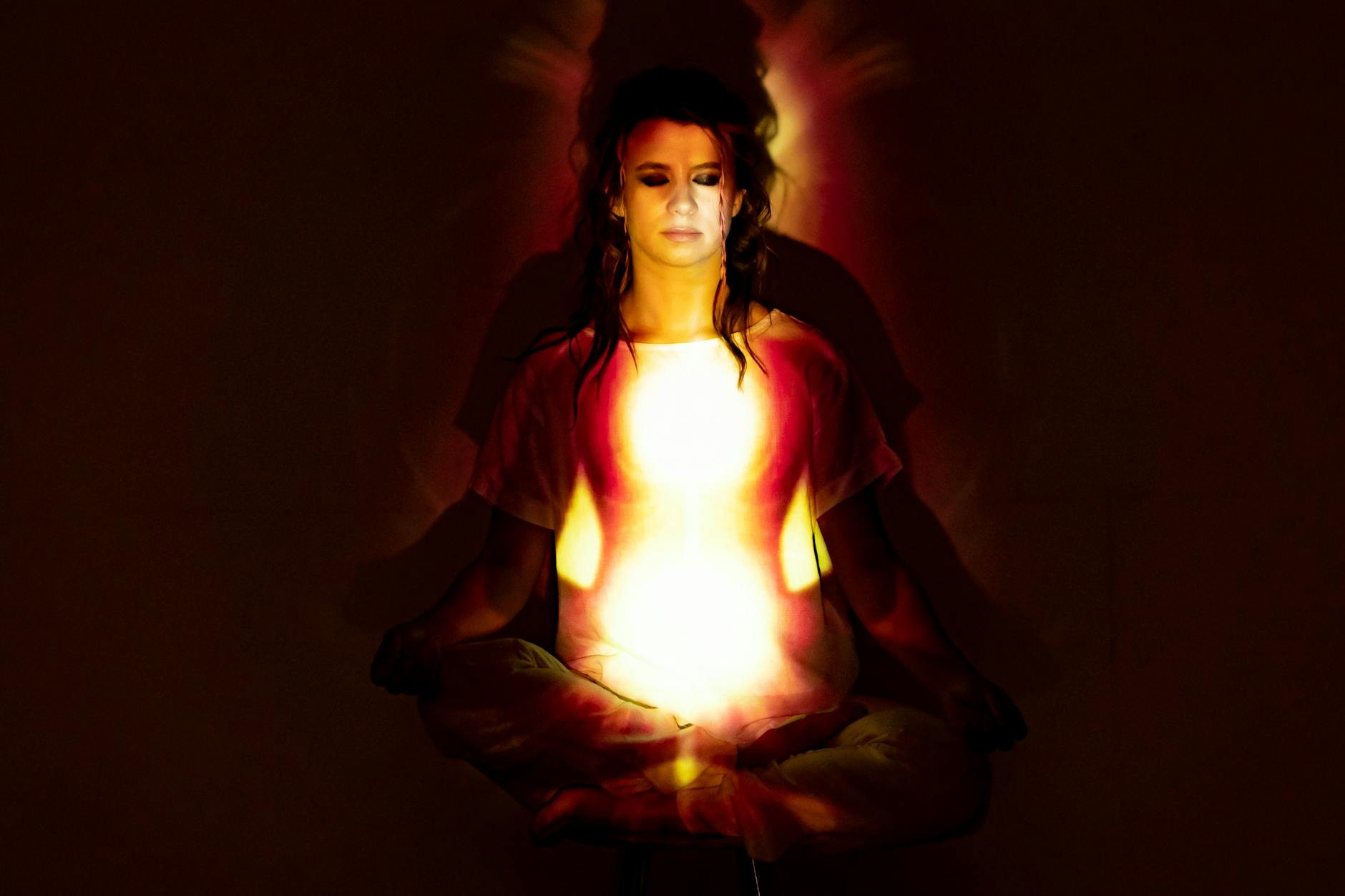 A woman in meditation surrounded by a radiant aura, symbolizing spiritual energy and enlightenment.