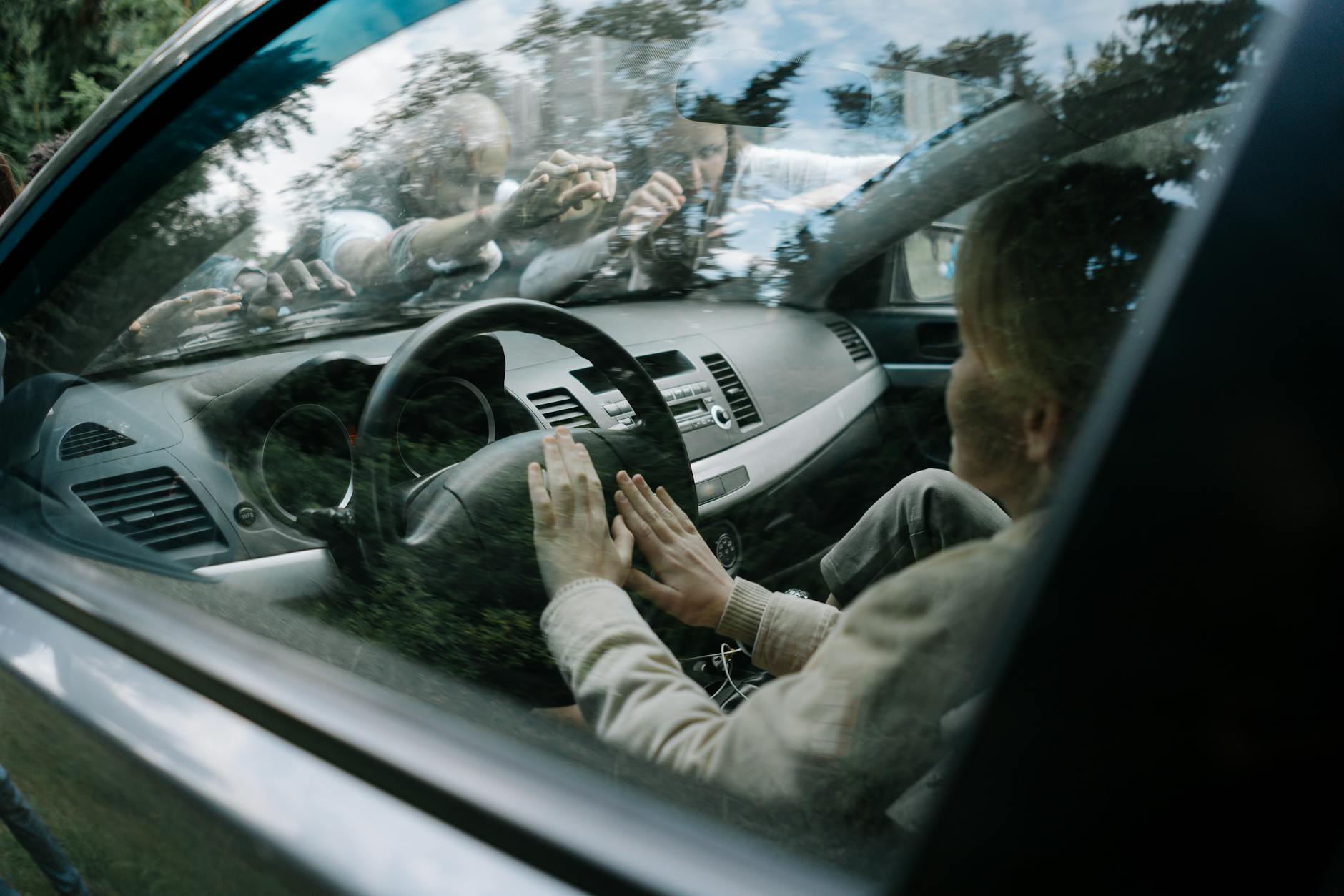 Intense moment of zombies attacking a car windshield in a suspenseful setting.