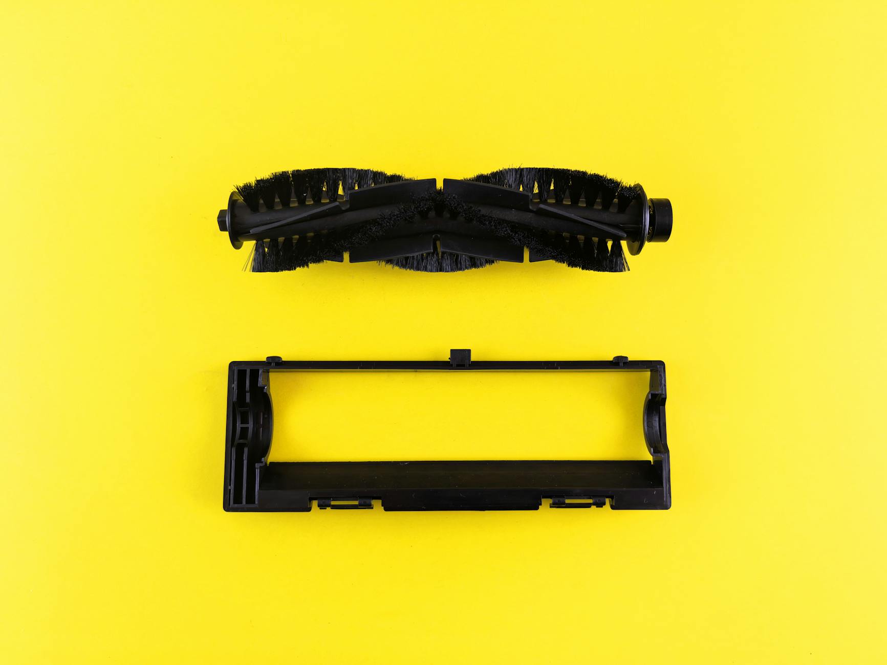 Close-up of vacuum cleaner components on vibrant yellow surface, highlighting maintenance and cleaning.