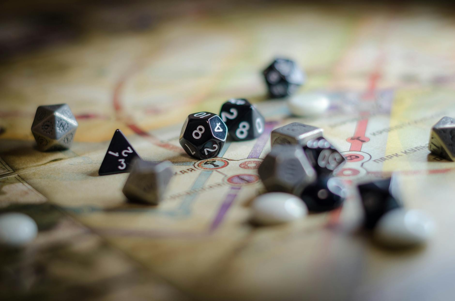 Focus on black and white polyhedral dice scattered on a board game map, suggesting strategy and chance.
