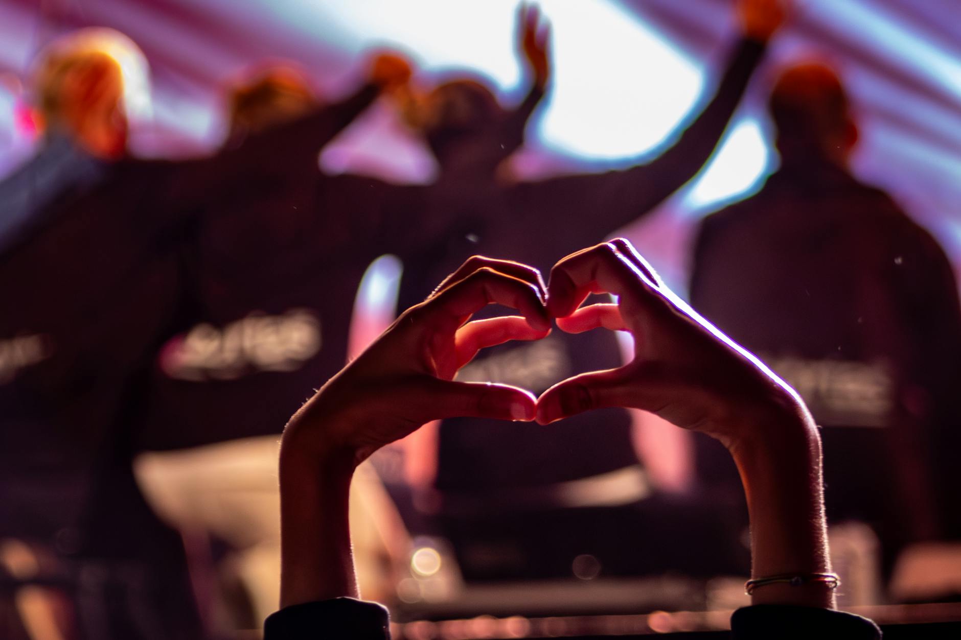 A silhouette of hands forming a heart at a lively night concert in Felgueiras, Portugal.