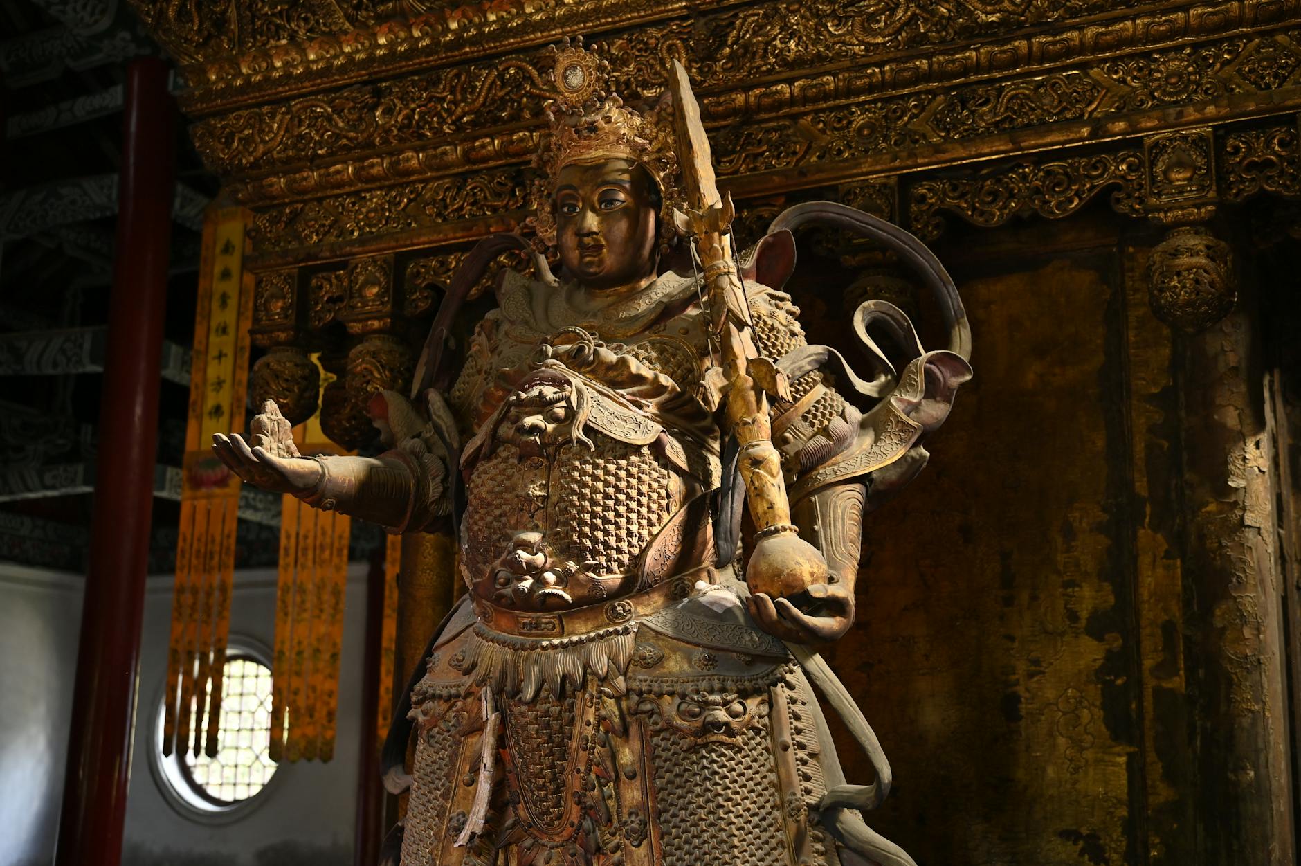 Stunning golden Buddhist statue with intricate details inside an ornate temple setting.