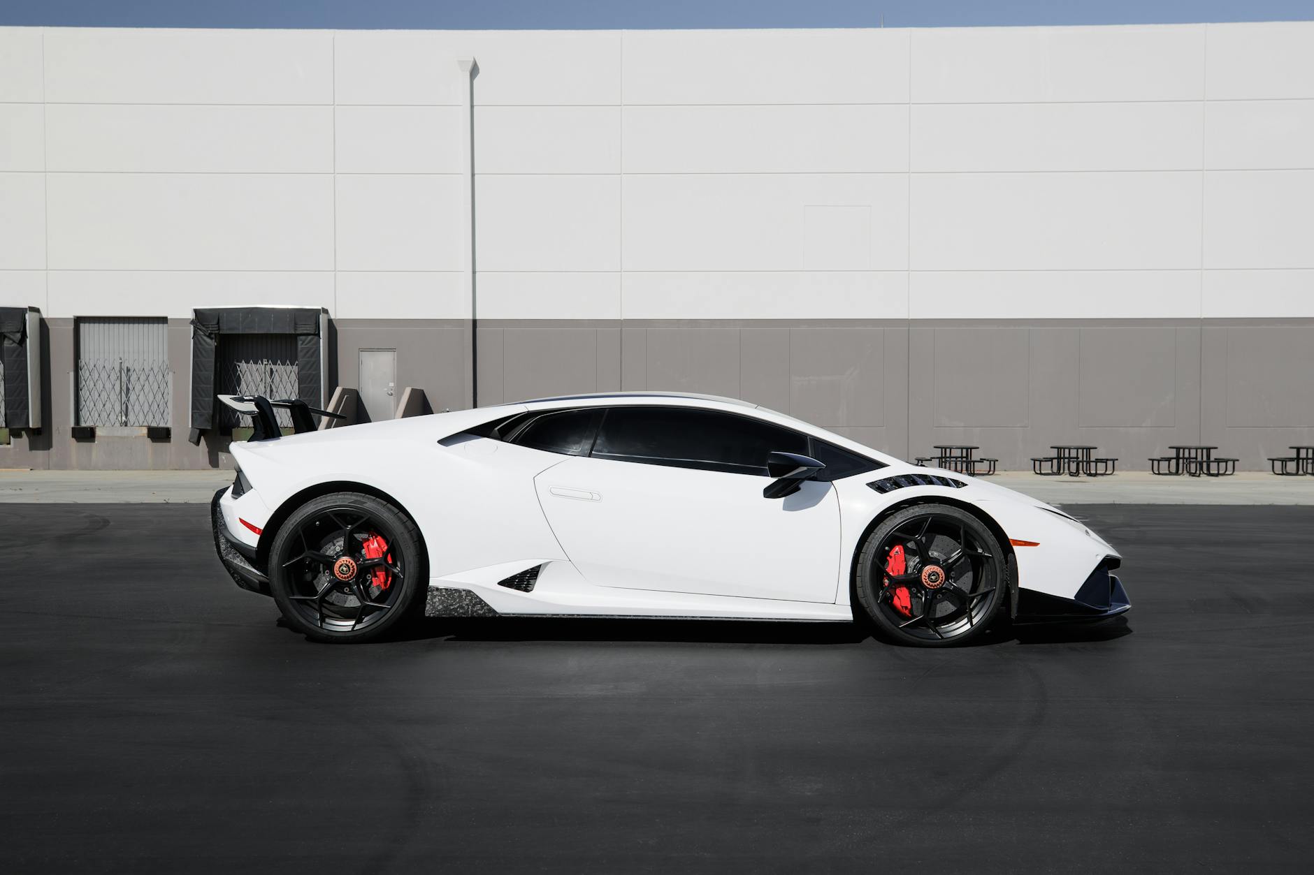 Side profile of a striking white Lamborghini Huracan parked on a city street.