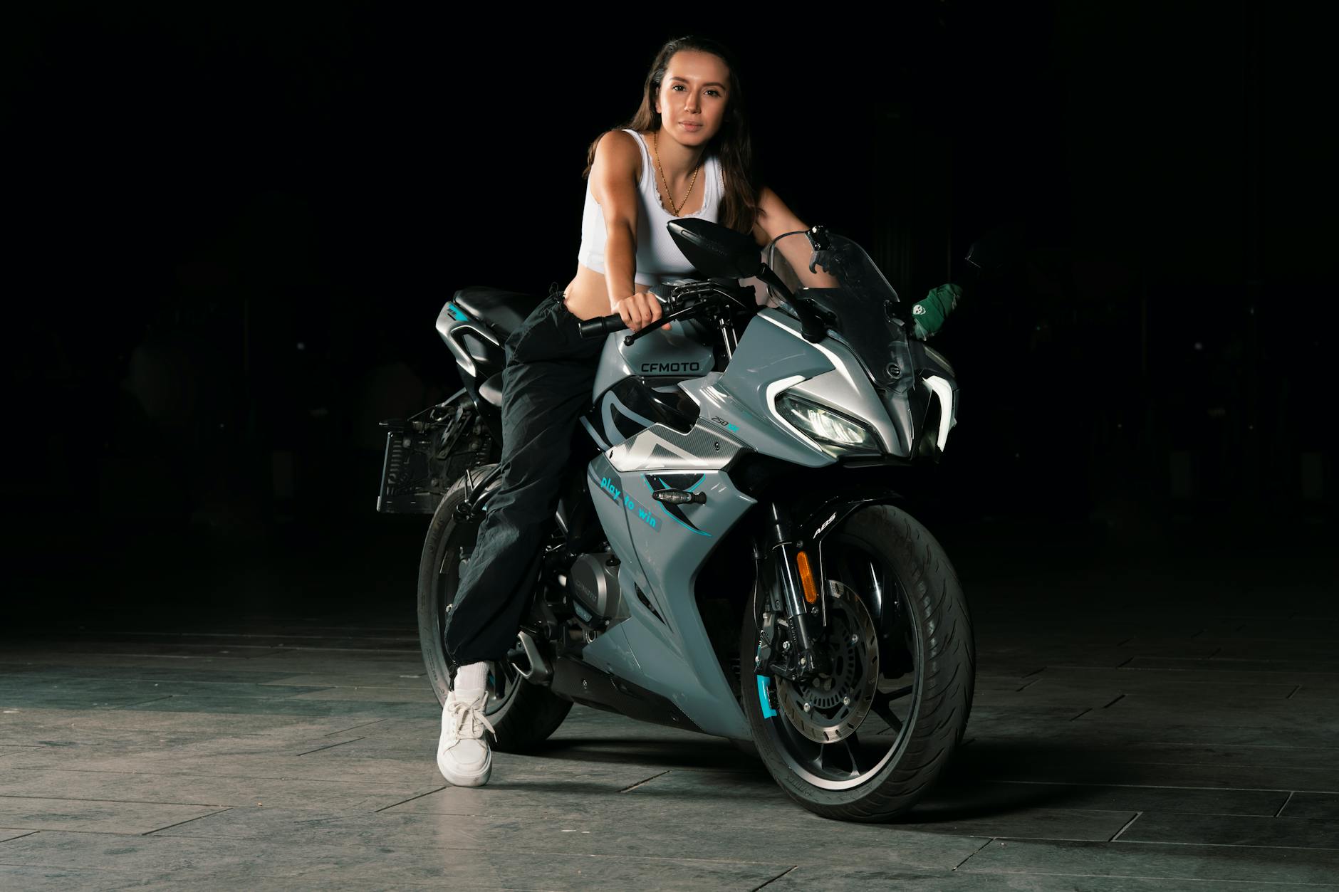 Confident woman sitting on a modern motorcycle in Istanbul during nighttime.