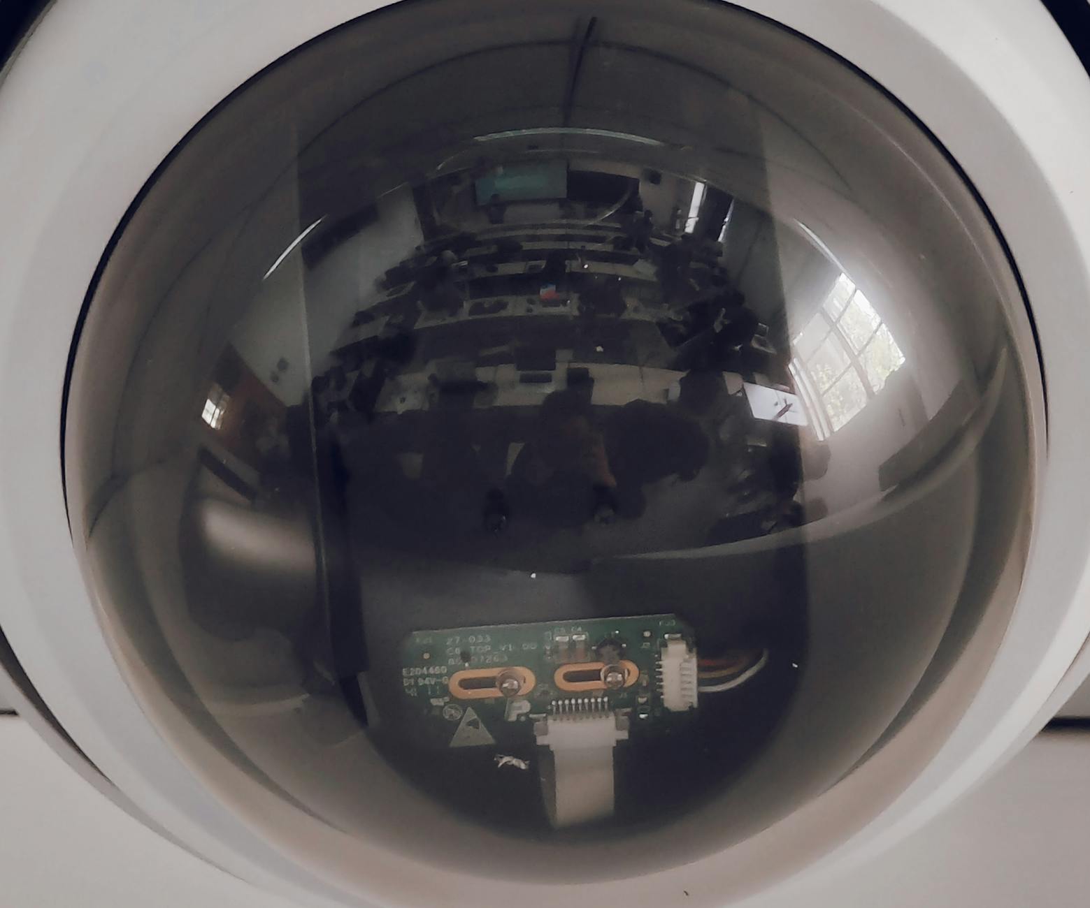 A close view of a surveillance dome camera reflecting an indoor setting.