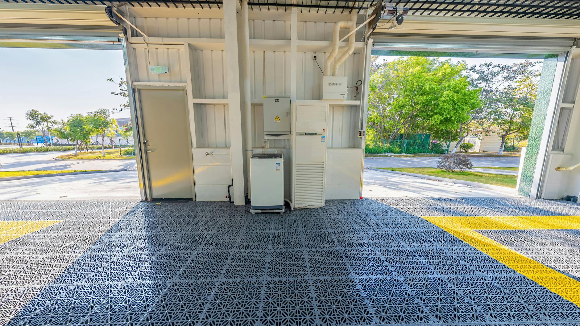 Spacious open garage with durable metal grid flooring and equipment setup facing outdoors.