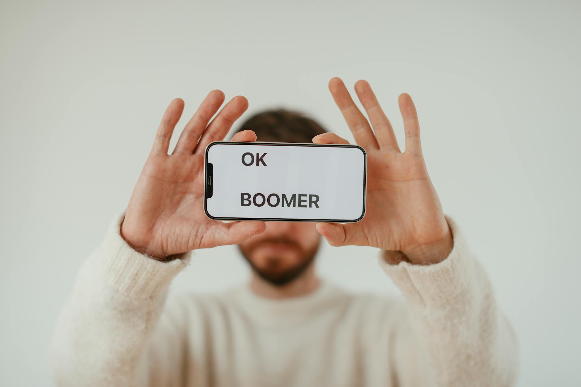 A man holding a smartphone with 'OK Boomer' text, emphasizing generational themes and internet culture.