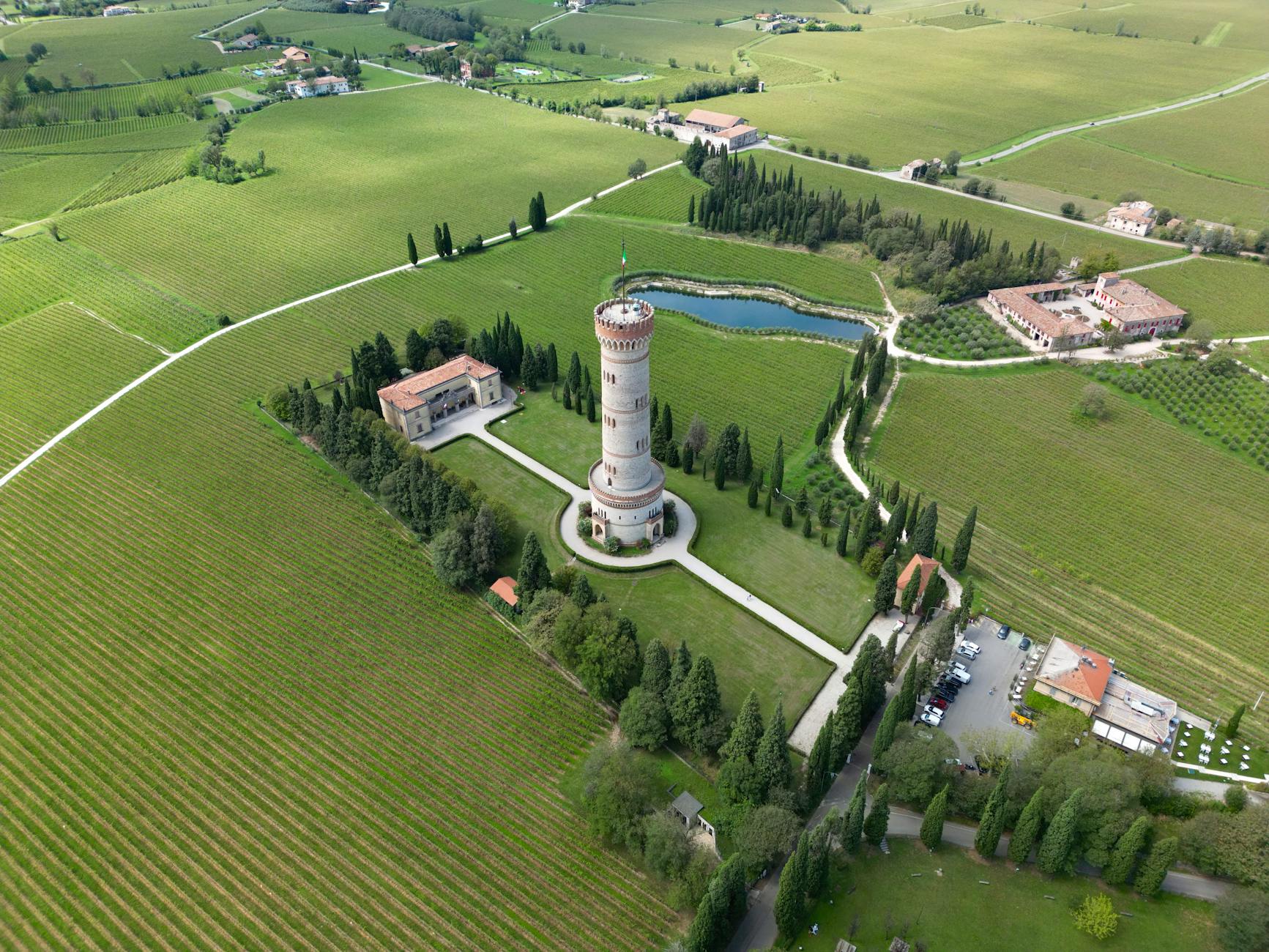 Drone shot capturing the historic San Martino della Battaglia Tower amidst lush Lombardy vineyards.