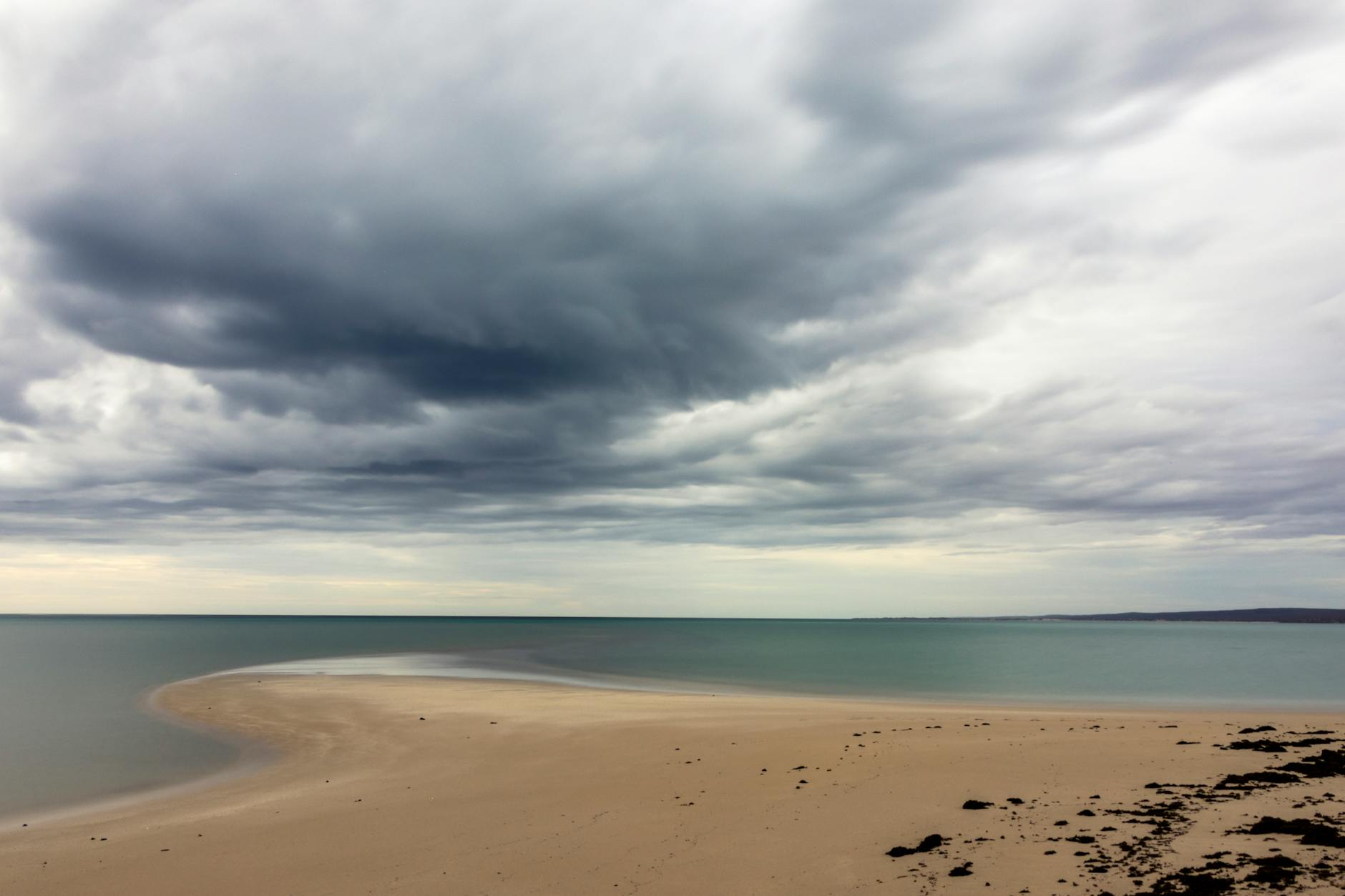 Dramatic clouds over a serene beach in Exmouth Gulf, Western Australia.