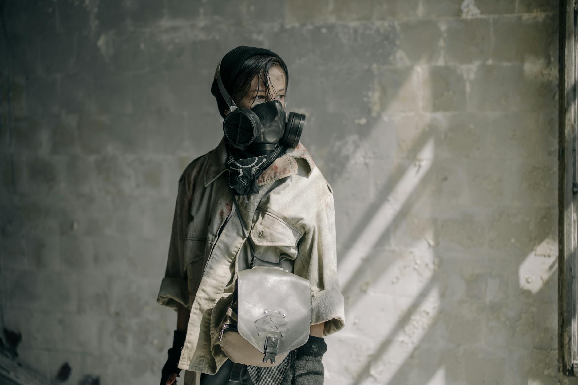 A young person with a gas mask stands in a dilapidated building, evoking a post-apocalyptic scene.