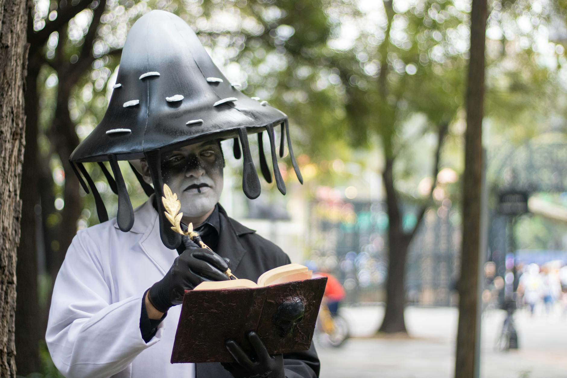 A person dressed as a mushroom reads an ornate book in a park setting, creating a whimsical scene.