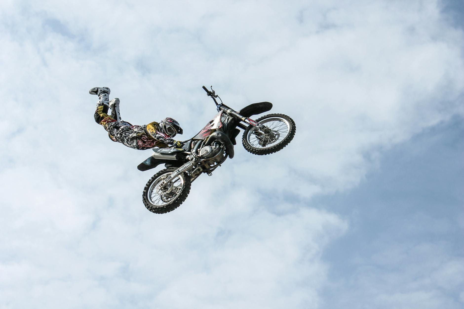 Exciting motocross action shot of a stunning aerial stunt against a bright sky.
